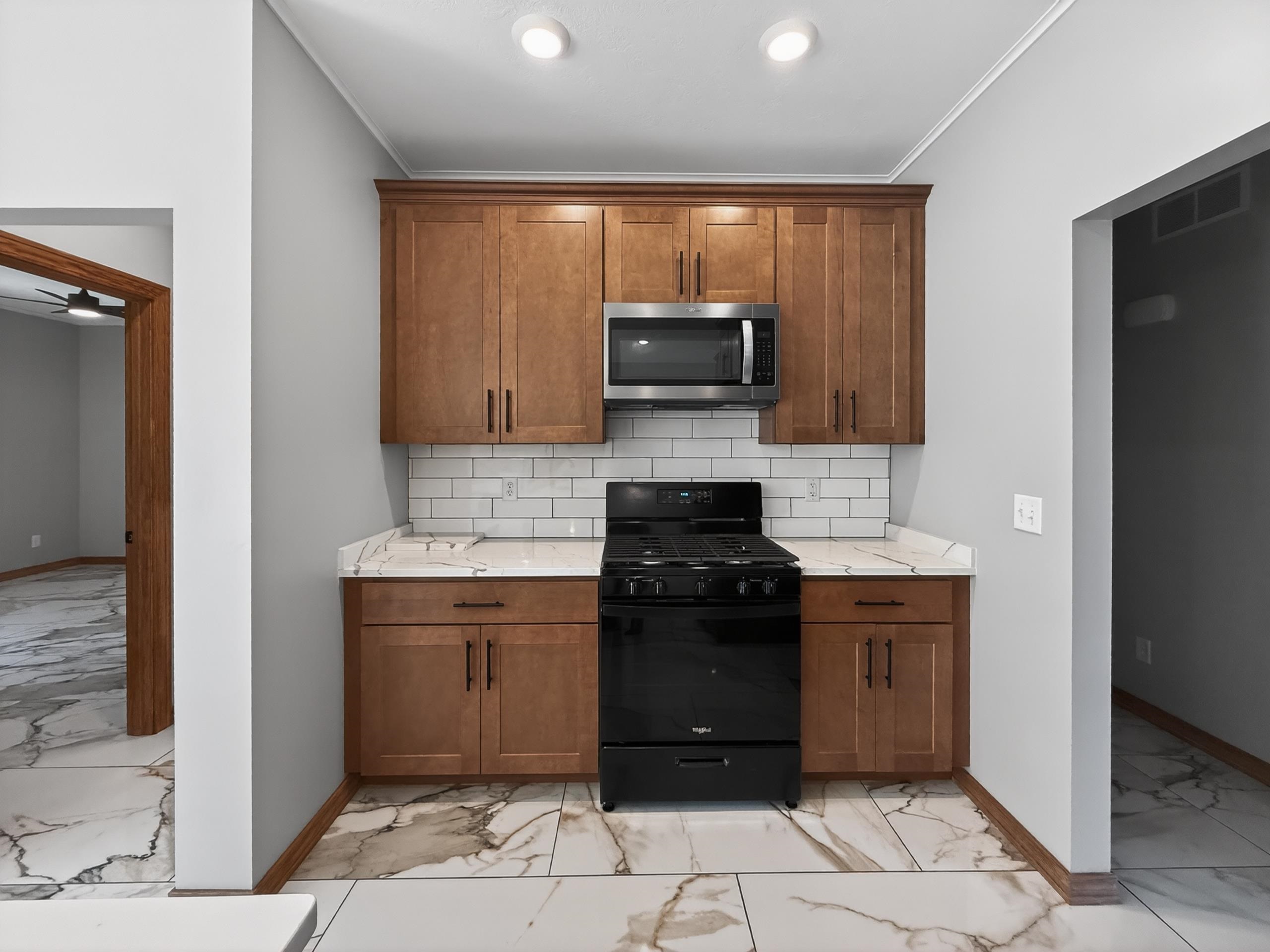 Kitchen area featuring wood-finish cabinetry, white subway tile backsplash, and a stainless steel over-the-range microwave