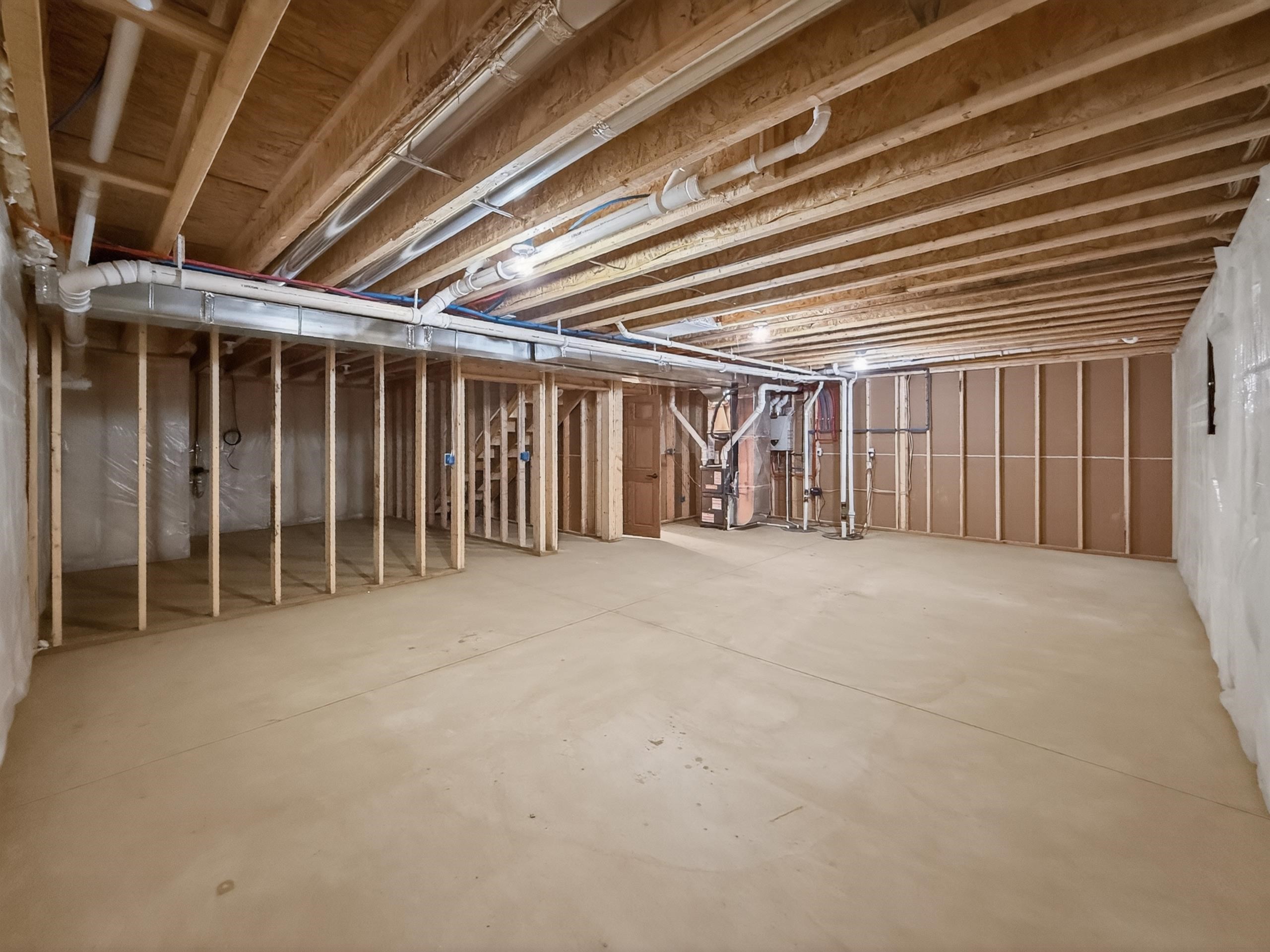 Unfinished lower level featuring exposed wood joists and subfloor, framing for future rooms, visible ductwork, and plumbing infrastructure