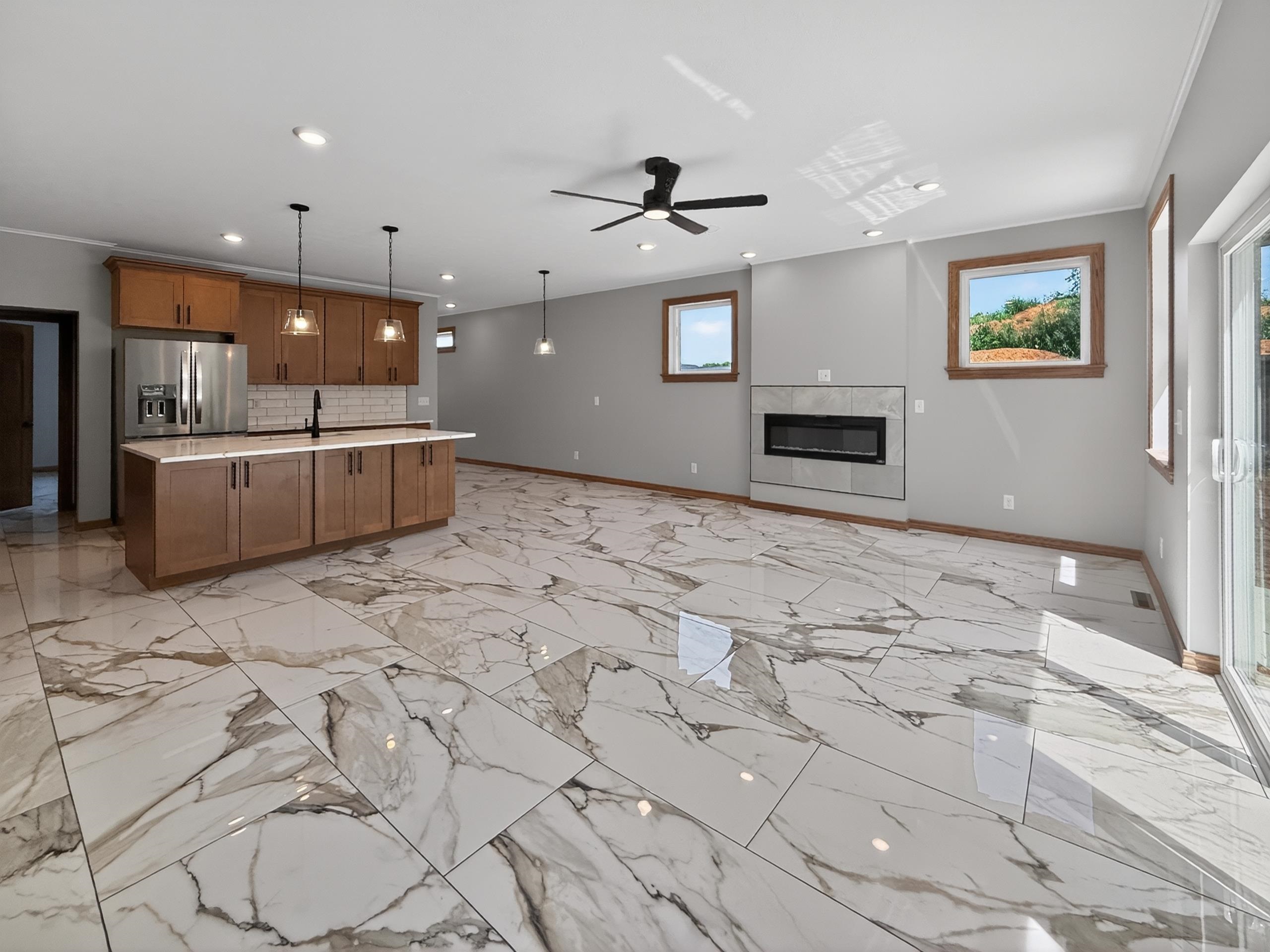 Spacious living area featuring large format marble-look tile flooring, a built-in linear fireplace with a tile surround, and recessed lighting