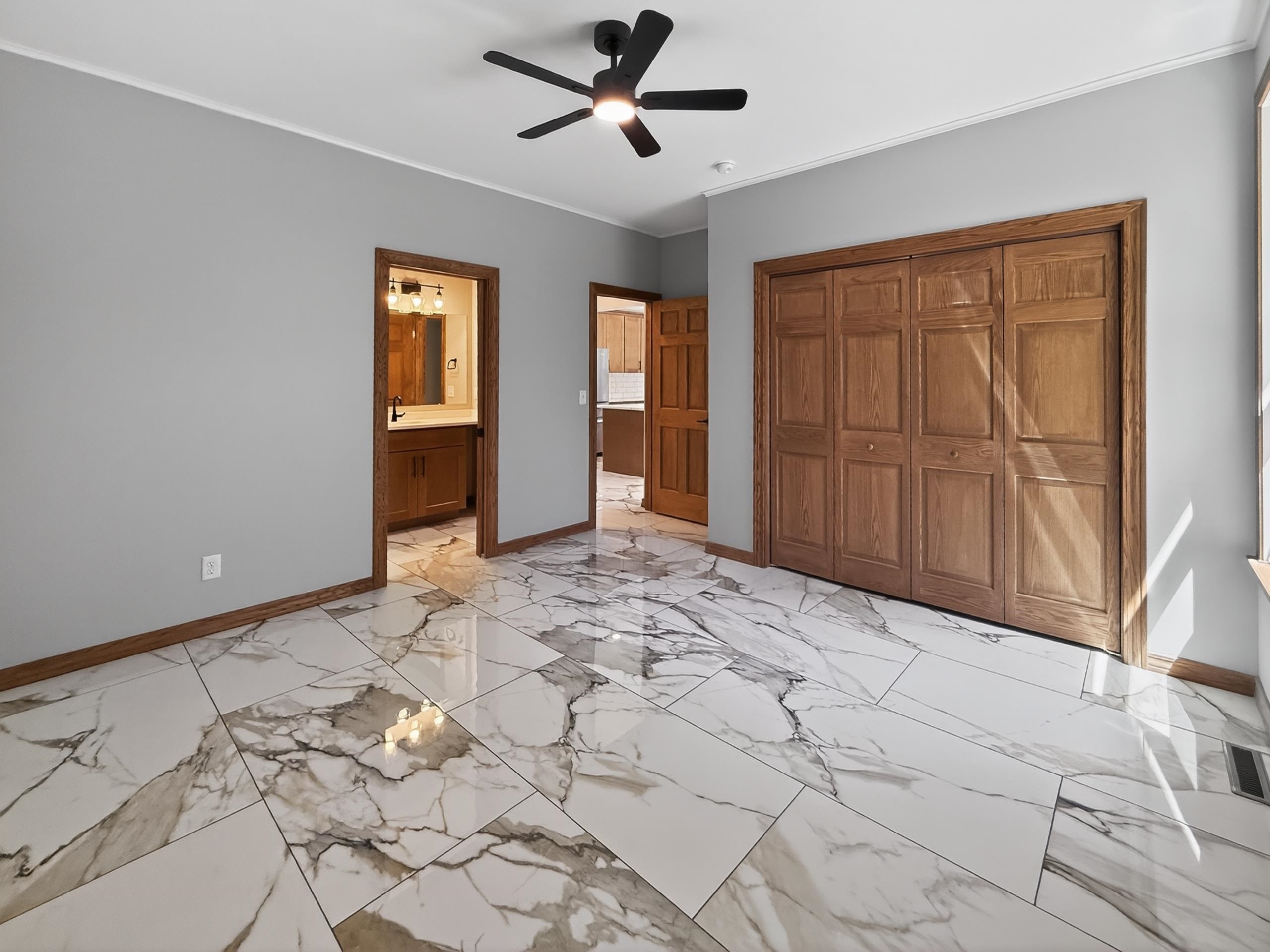 Expansive room featuring large format marble-look tile flooring, light gray walls, and natural wood trim throughout