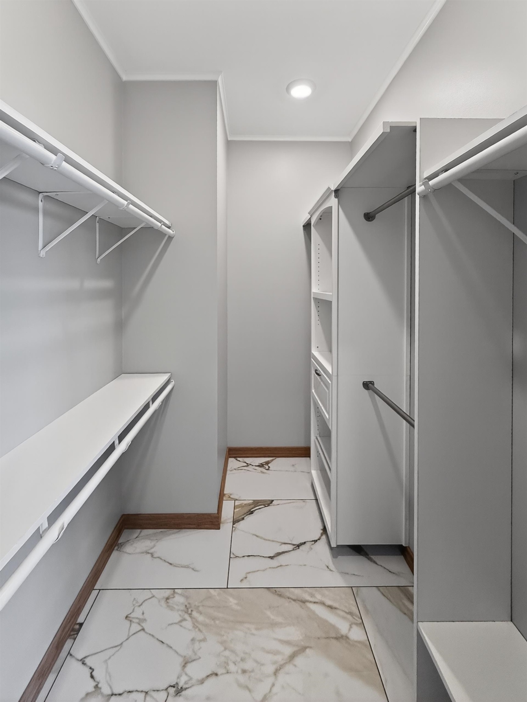 Walk-in closet featuring white built-in shelving, hanging rods, and integrated drawers