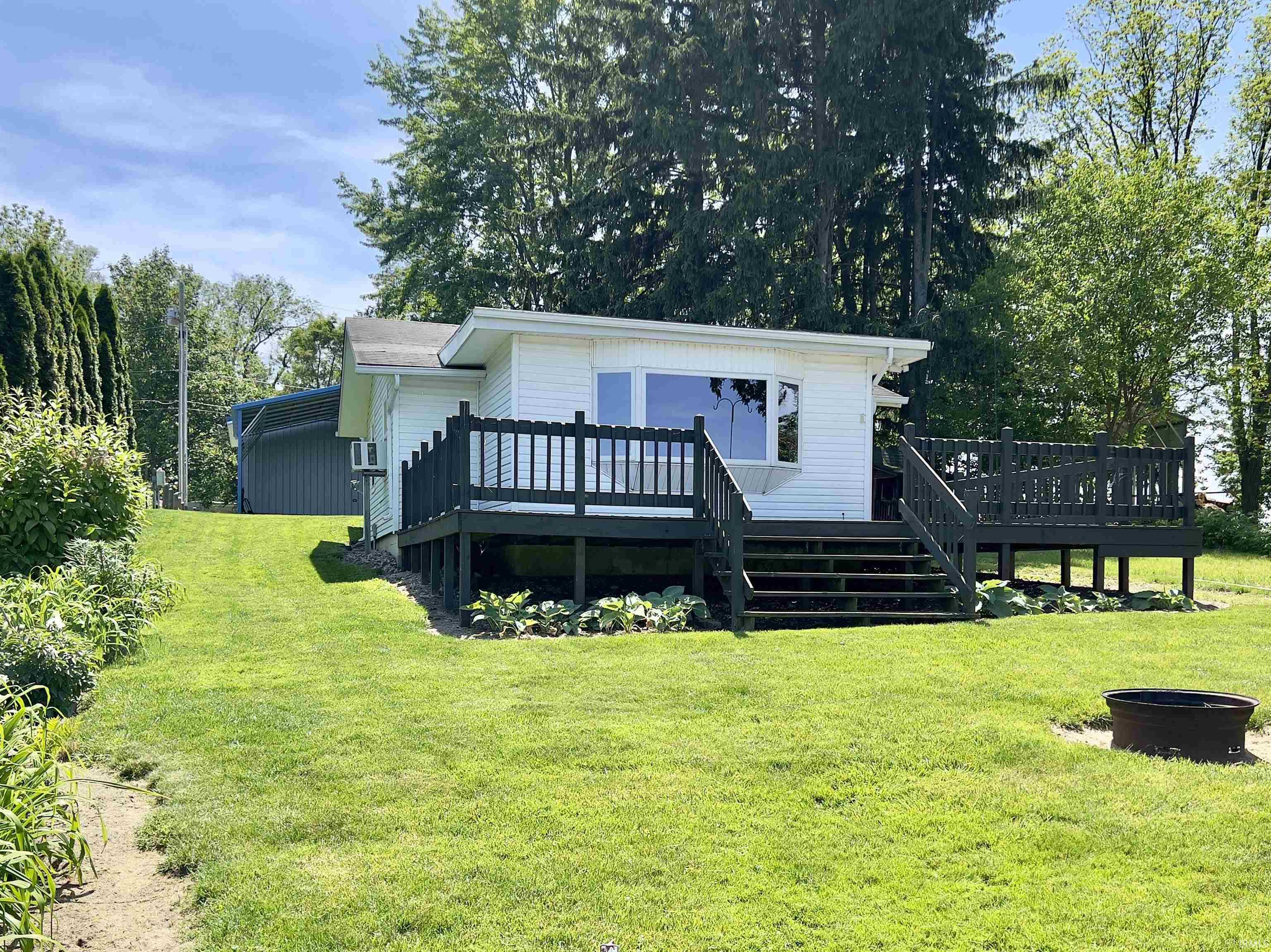 White siding exterior with an expansive dark-stained wood deck featuring a multi-level design and railings
