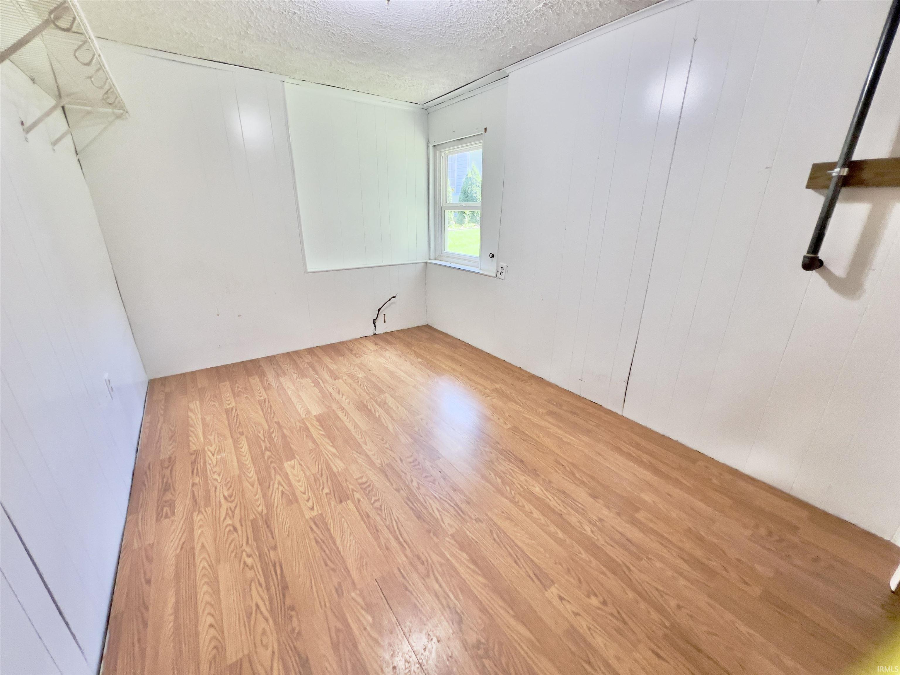 Room with wood-finish flooring and white paneled walls
