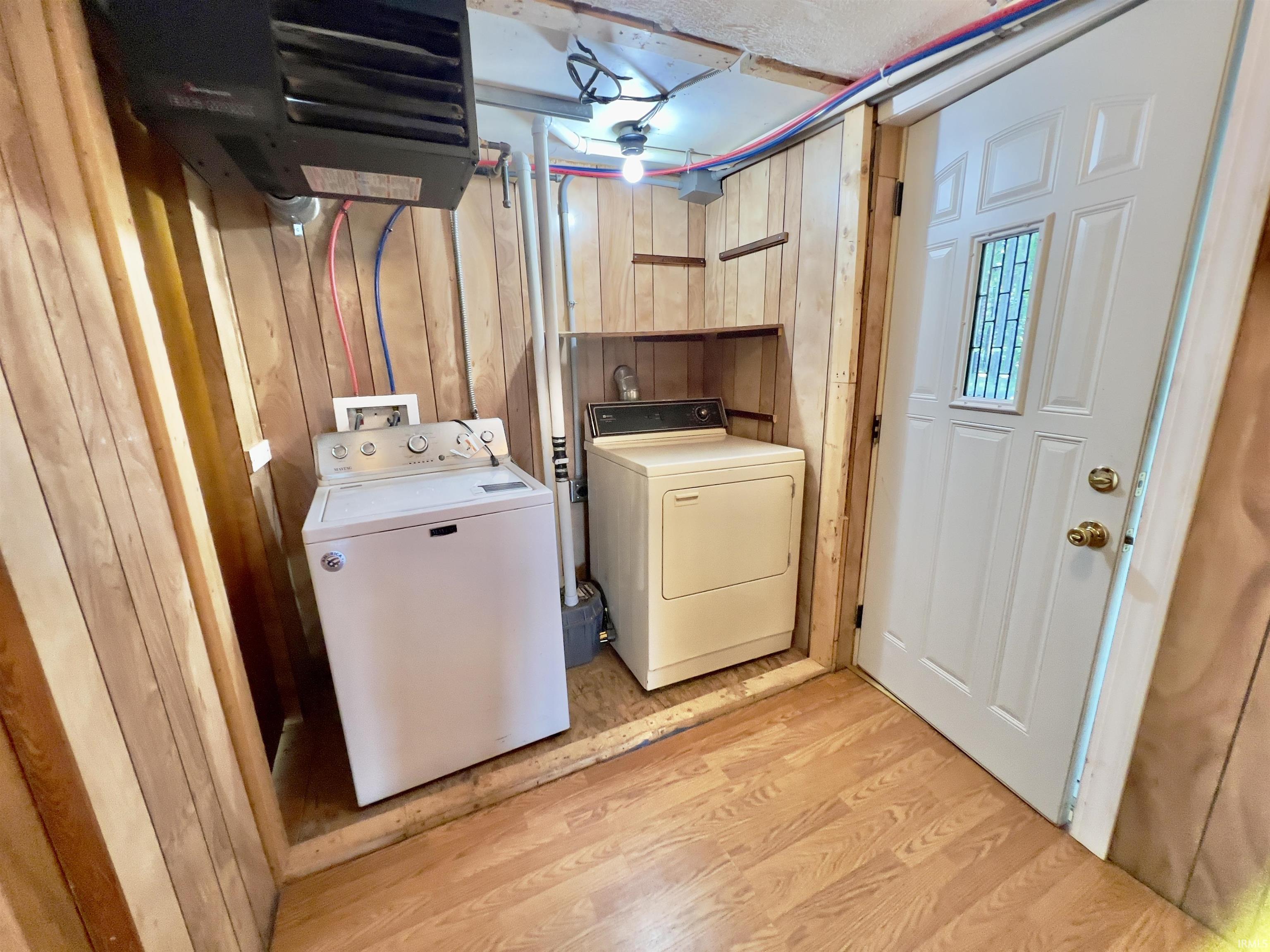 Laundry area with wood-finish flooring and paneled walls