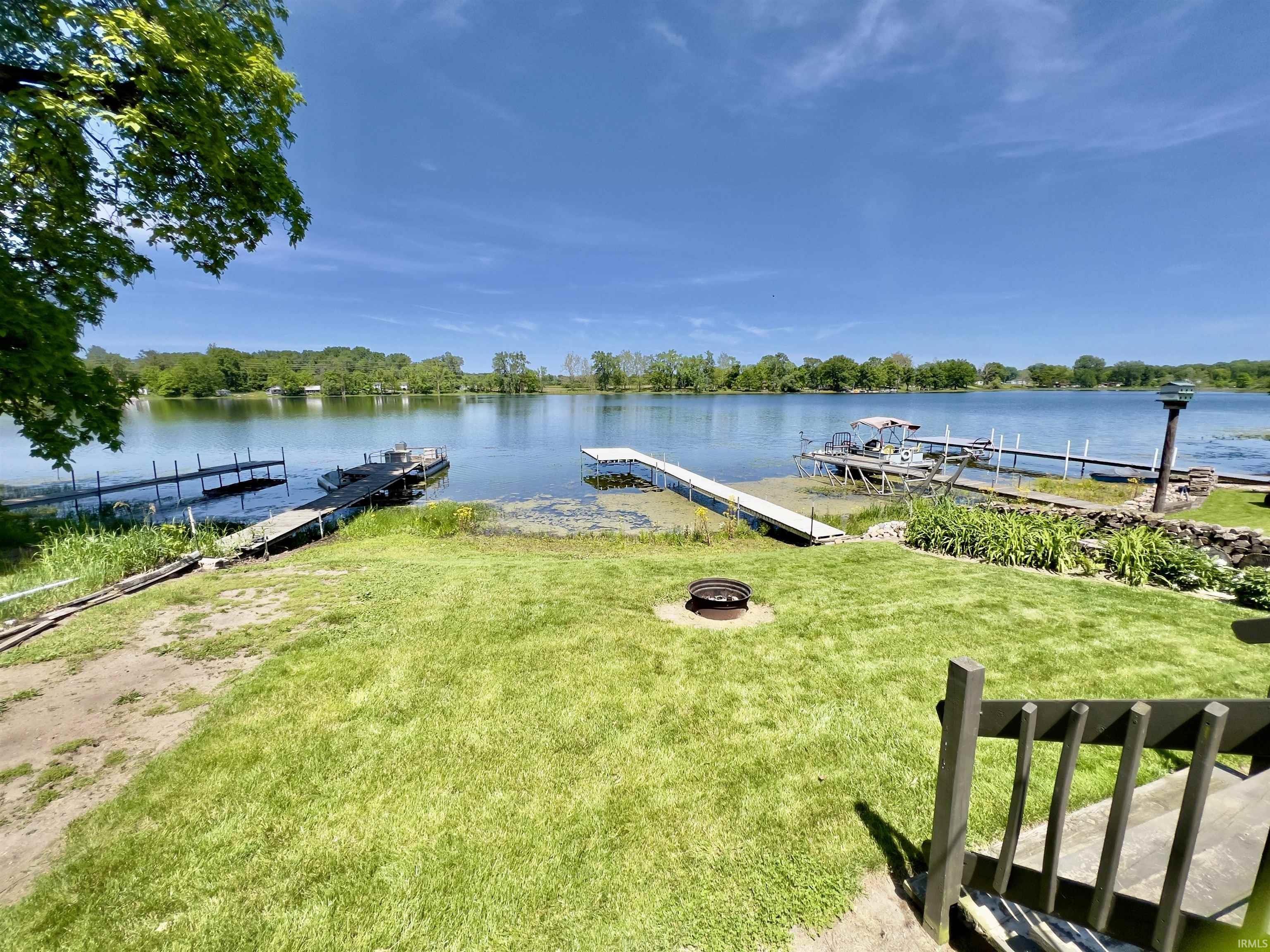 Waterfront property featuring a large pier, spacious lawn, and fire pit