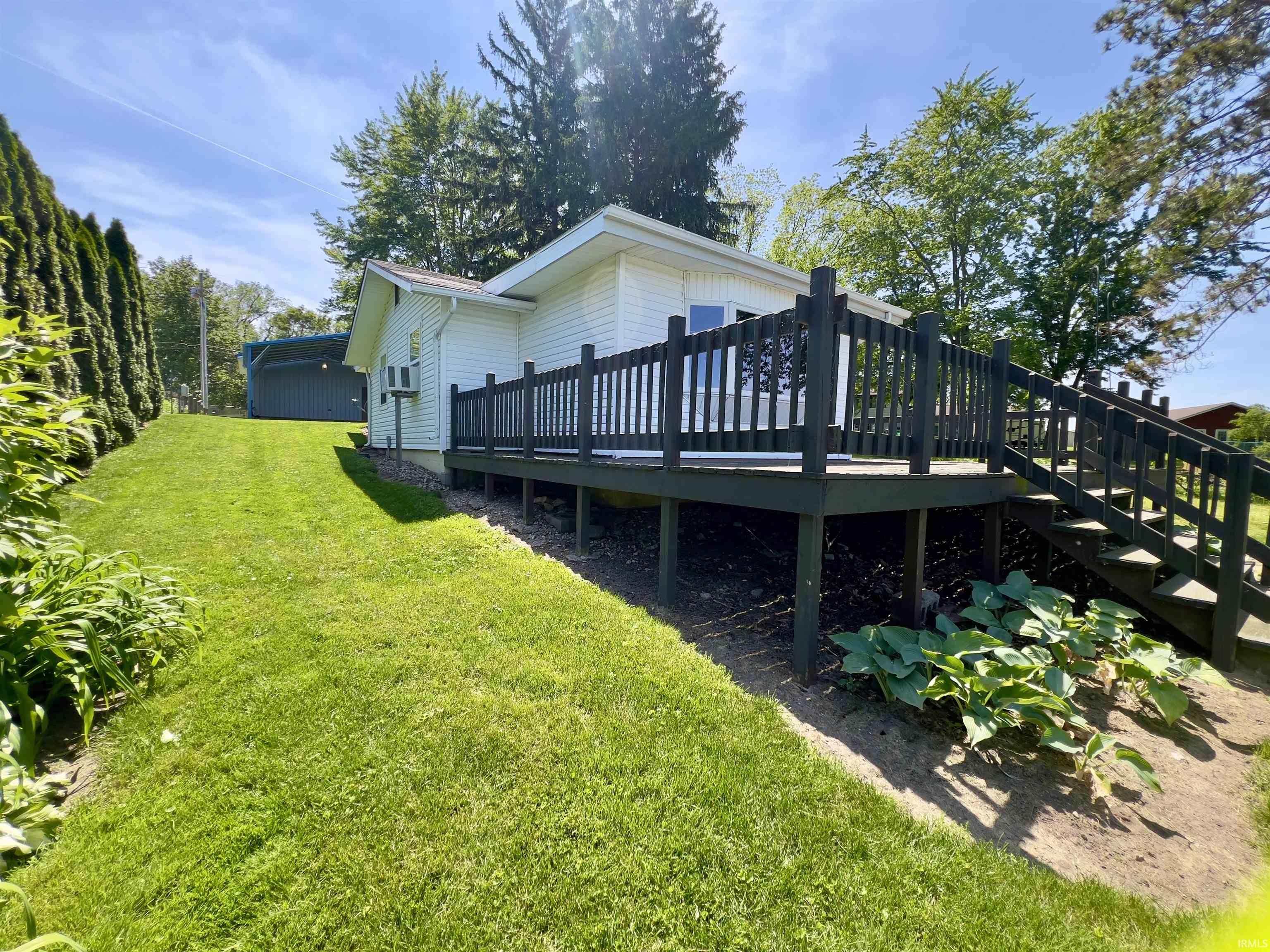 Exterior featuring a spacious wood deck with dark railing, extending from the residence