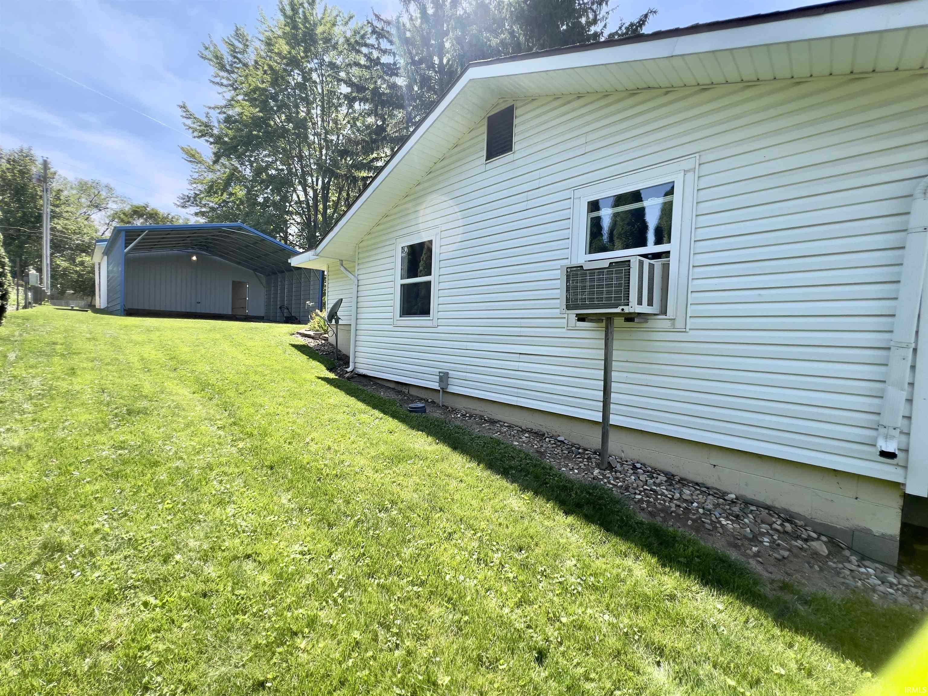 Expansive lawn featuring a detached carport structure