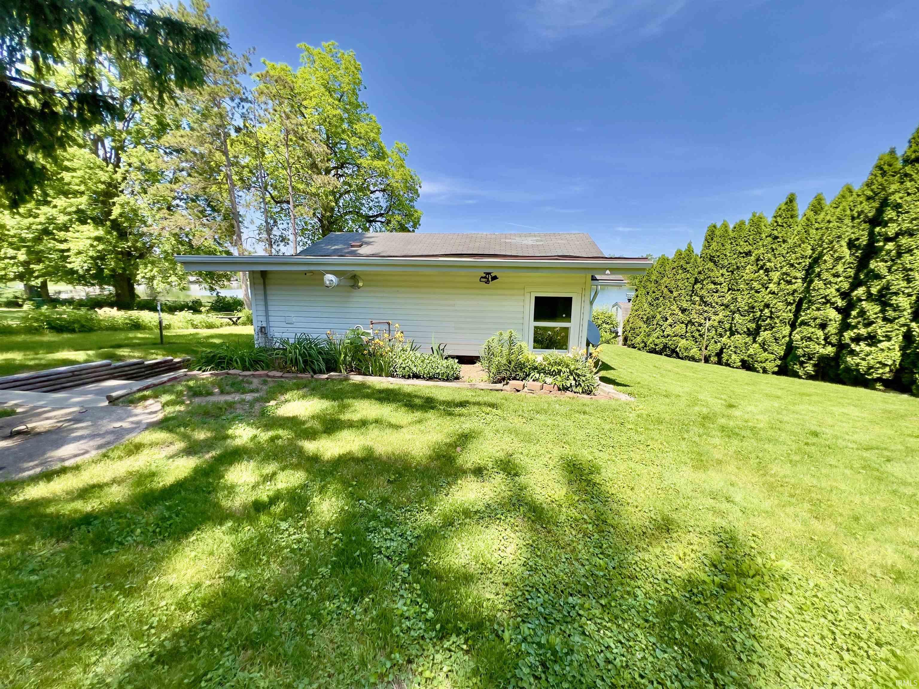 Rear exterior with white vinyl siding, a single window, and a planted garden bed