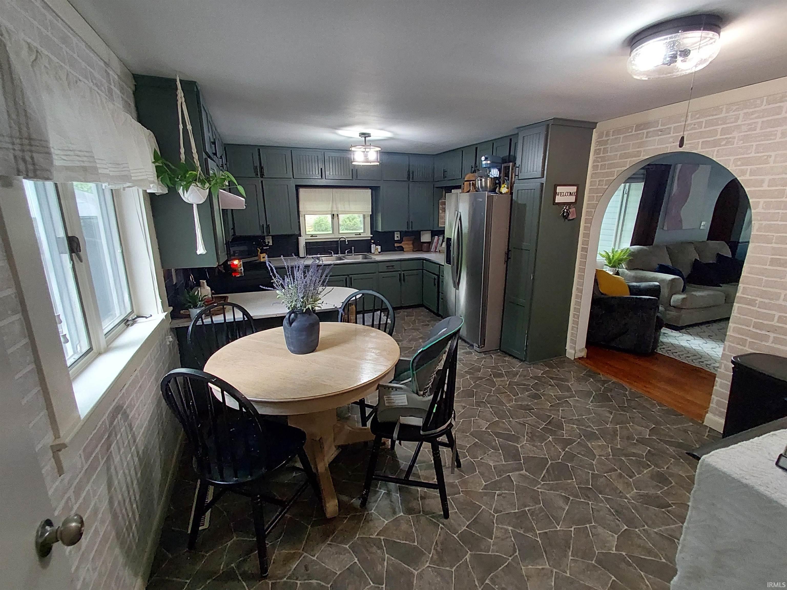 Kitchen featuring dark green cabinetry, white countertops, and irregular stone-pattern flooring