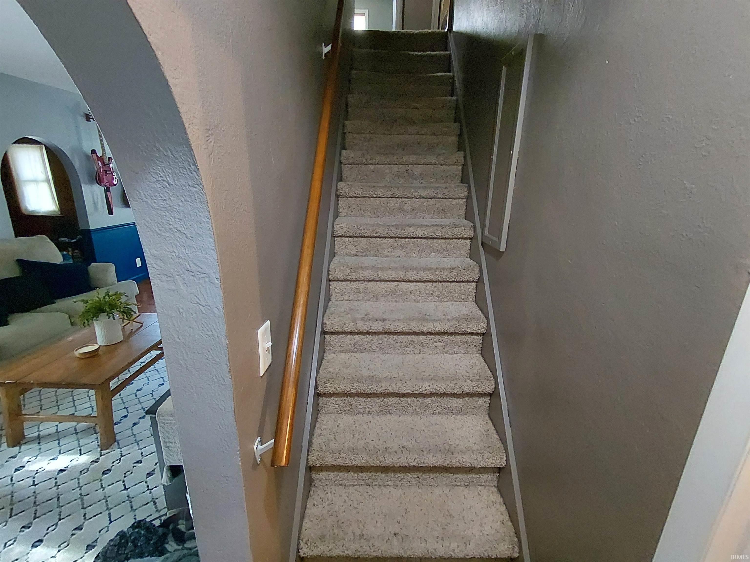 Carpeted staircase with a wood handrail