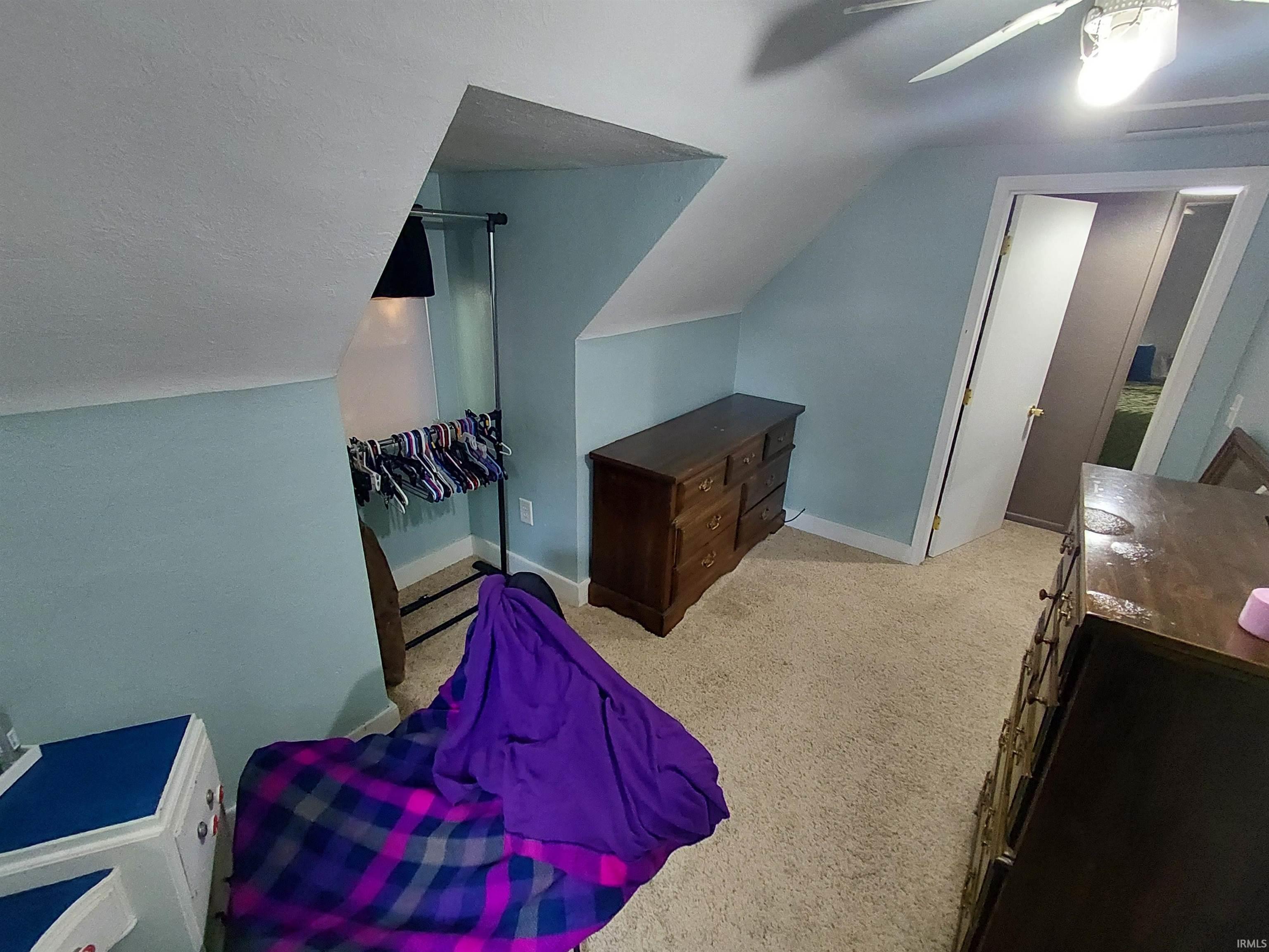 Carpeted room featuring a sloped ceiling, light blue walls, and white baseboards