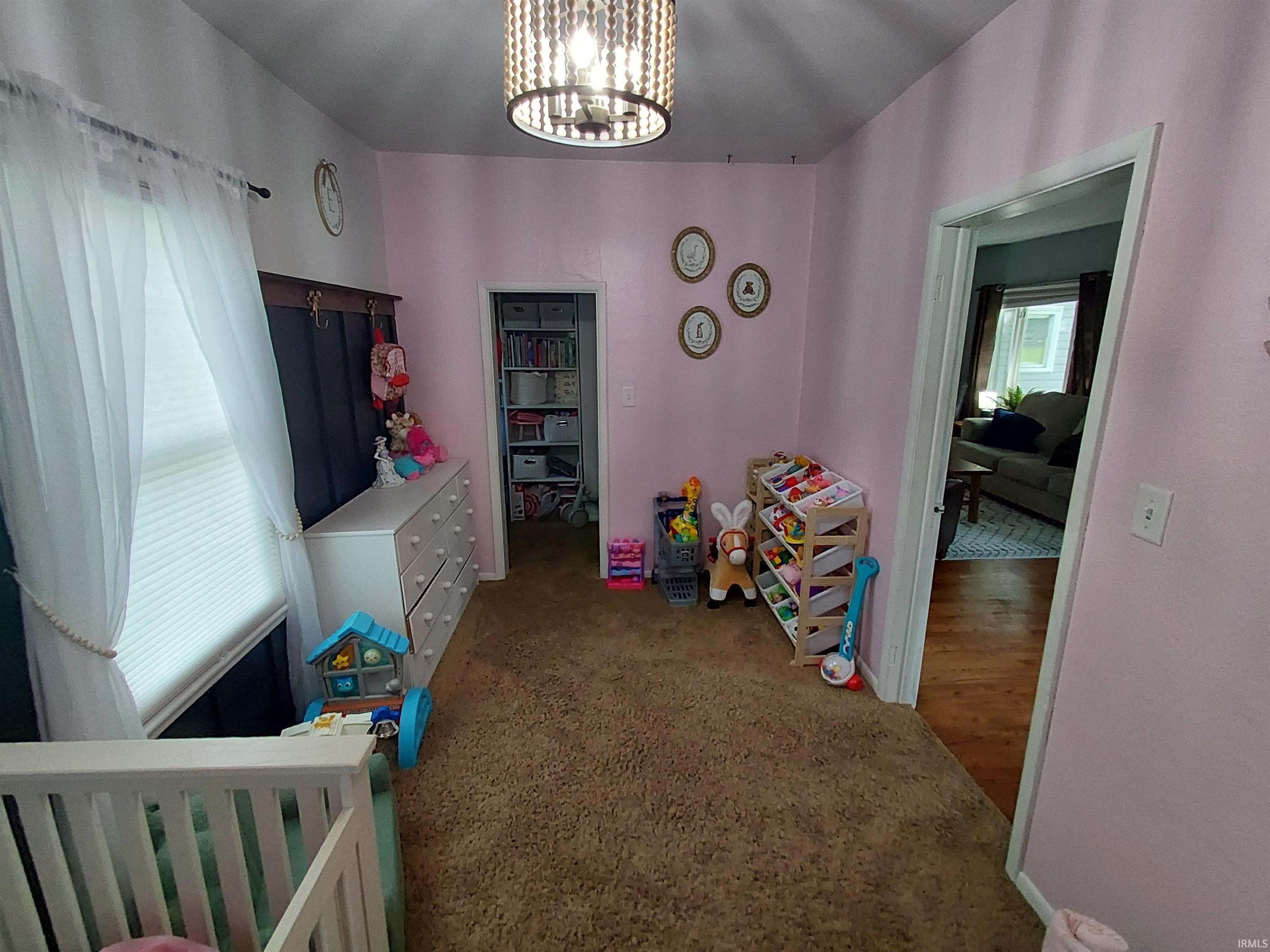 Room featuring soft pink walls, a window with horizontal blinds, and a built-in closet with shelving