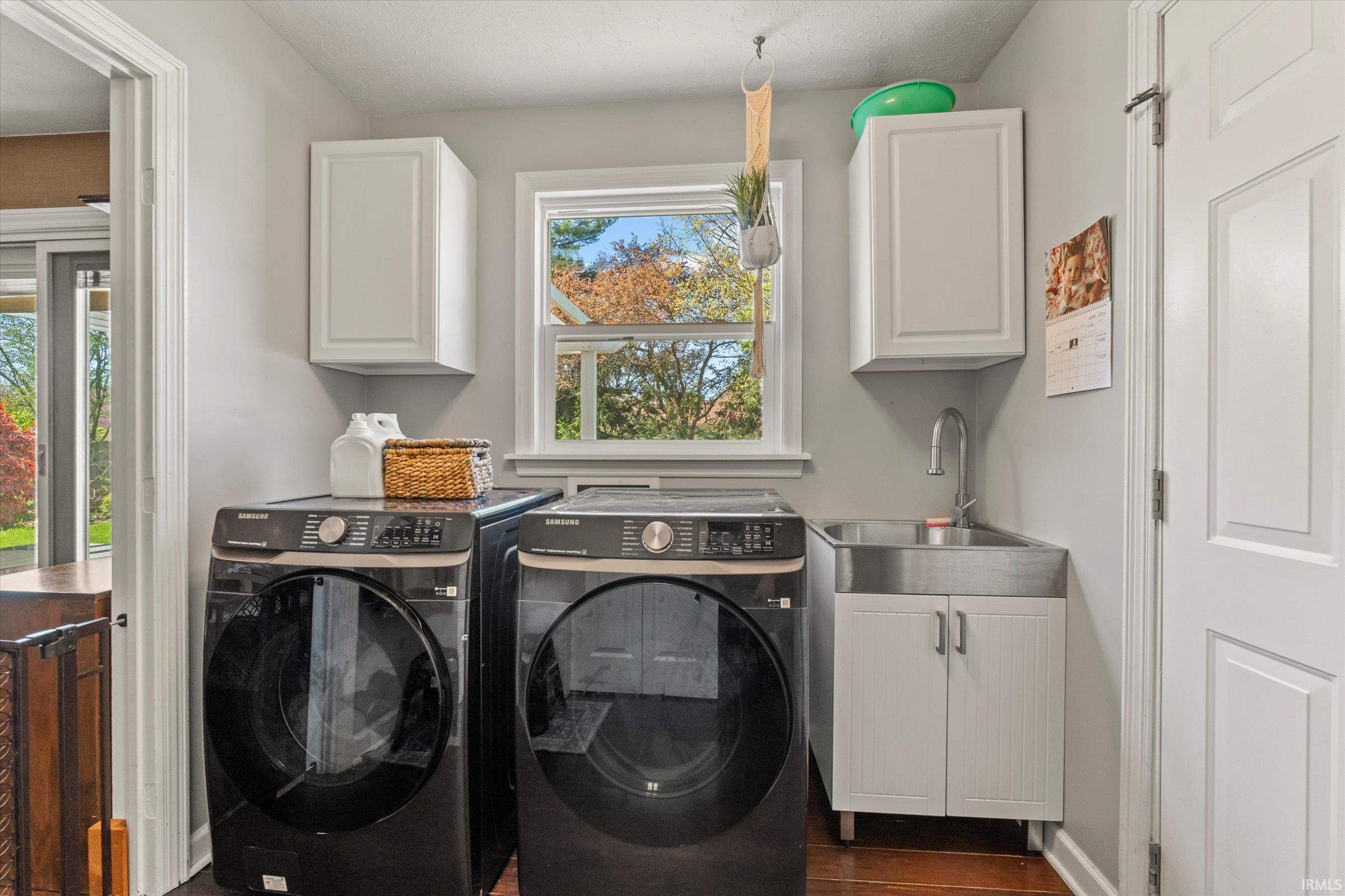 Dedicated laundry space featuring a utility sink with a high-arc faucet, wall-mounted cabinetry, and a bright window