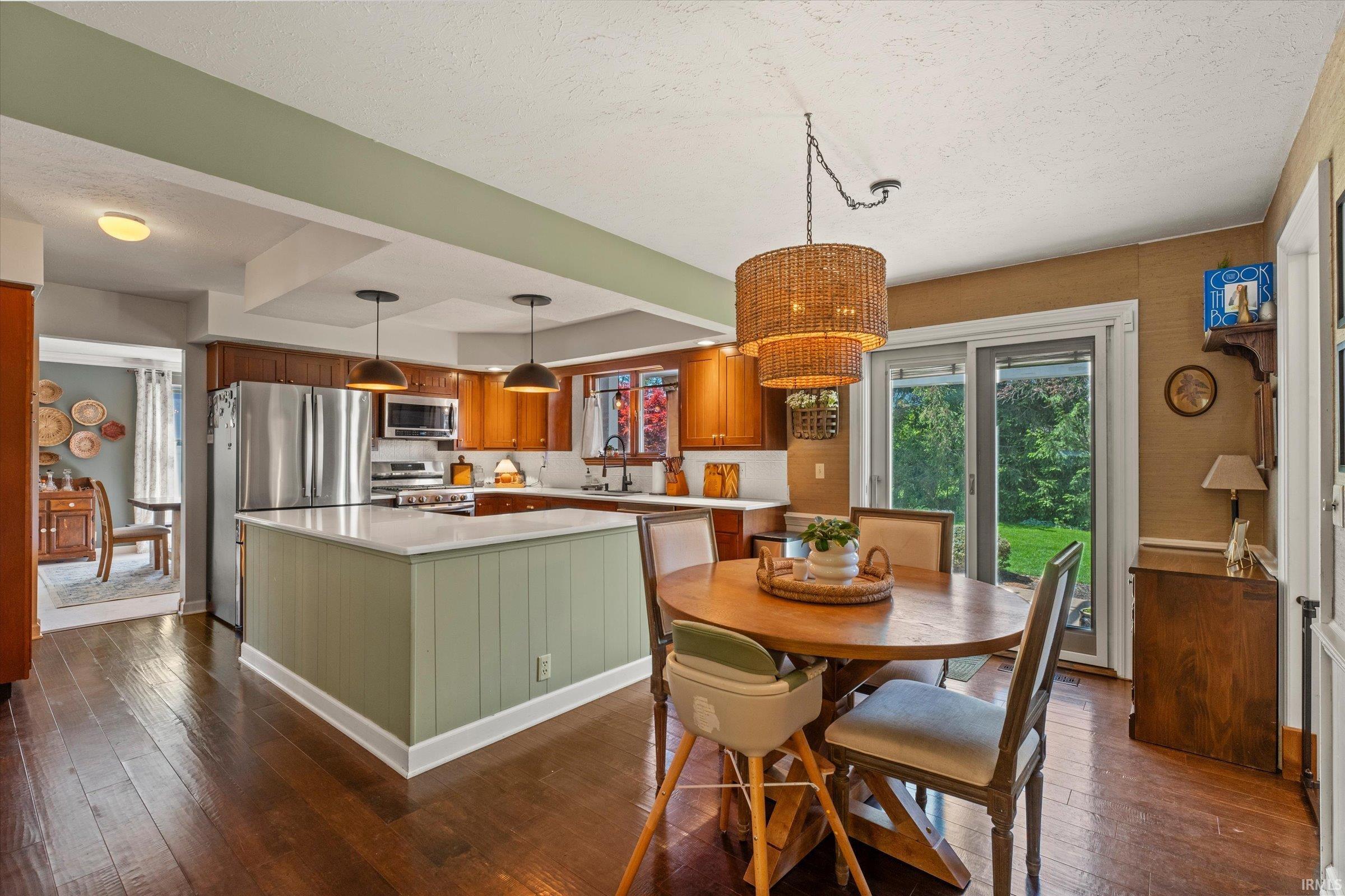 Kitchen featuring wood-finish flooring, a central island with paneling, stainless steel appliances, and wood cabinetry