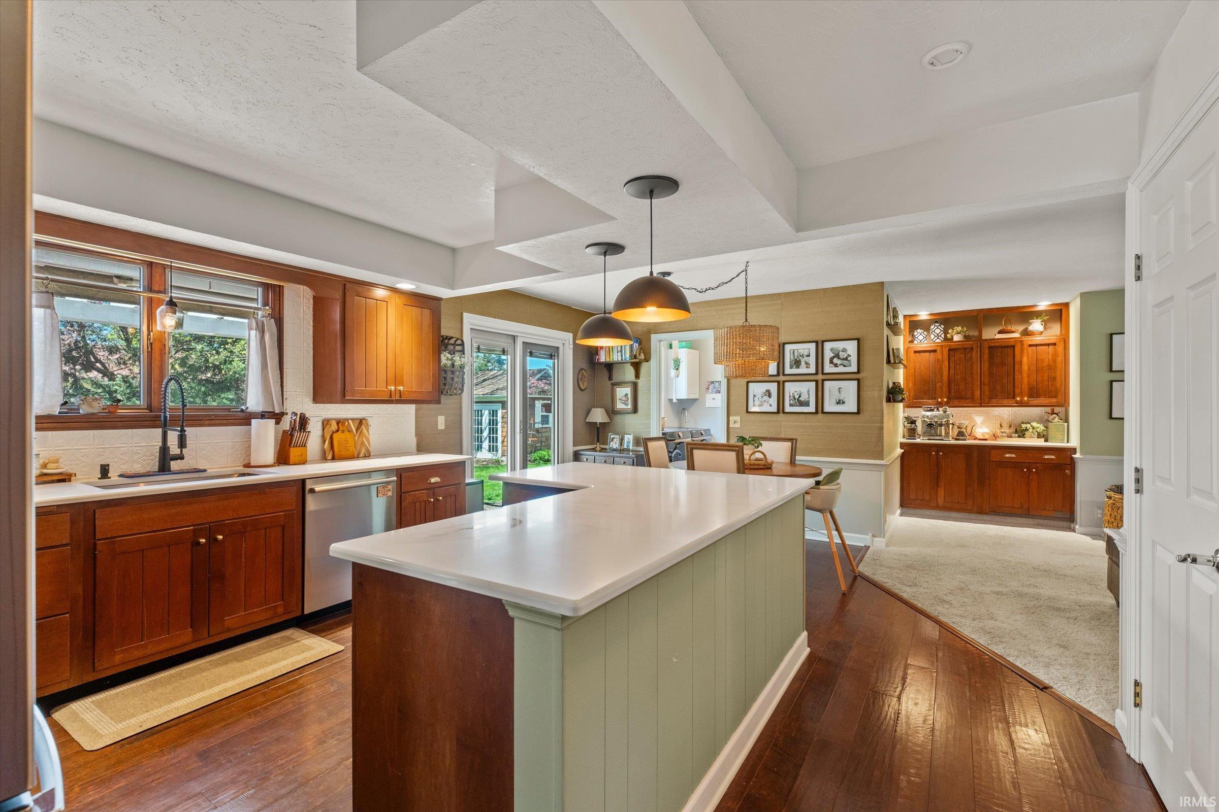 Kitchen featuring wood-finish flooring, wood cabinetry, white countertops, and a center island with pendant lighting