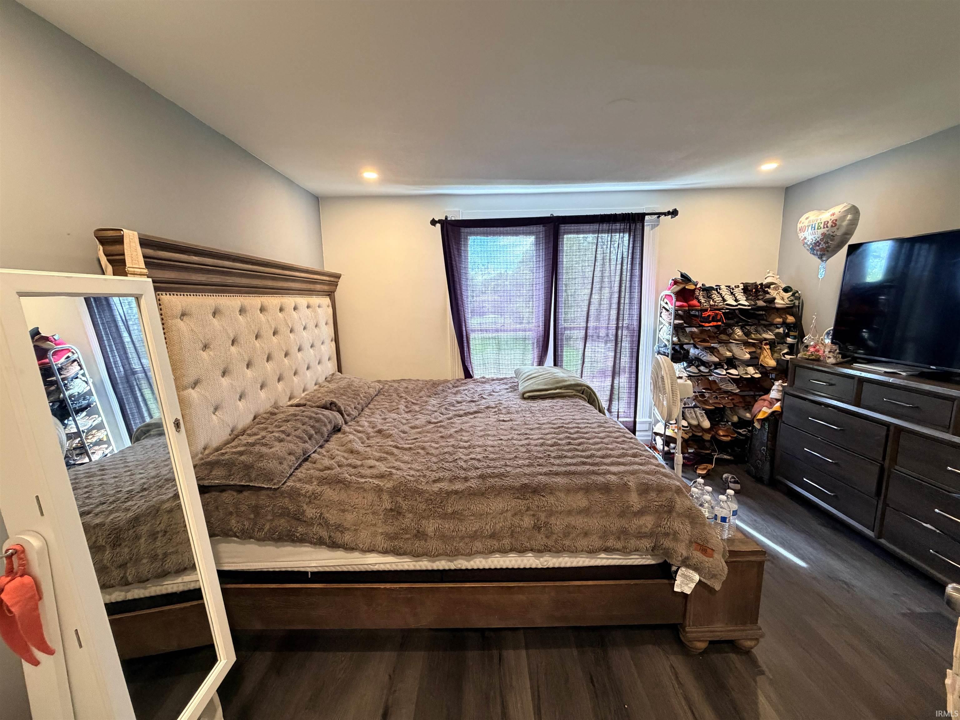 Spacious room featuring wood-finish flooring, recessed lighting, and a window with sheer privacy coverings