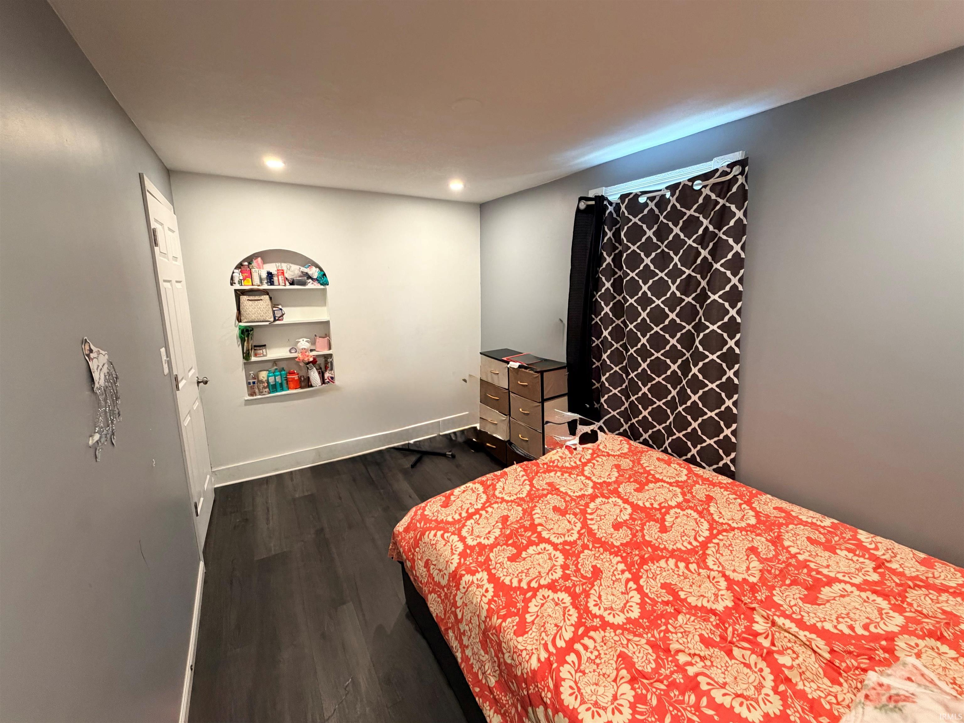 Room featuring recessed lighting, dark wood-finish flooring, and a built-in arched wall niche with shelving