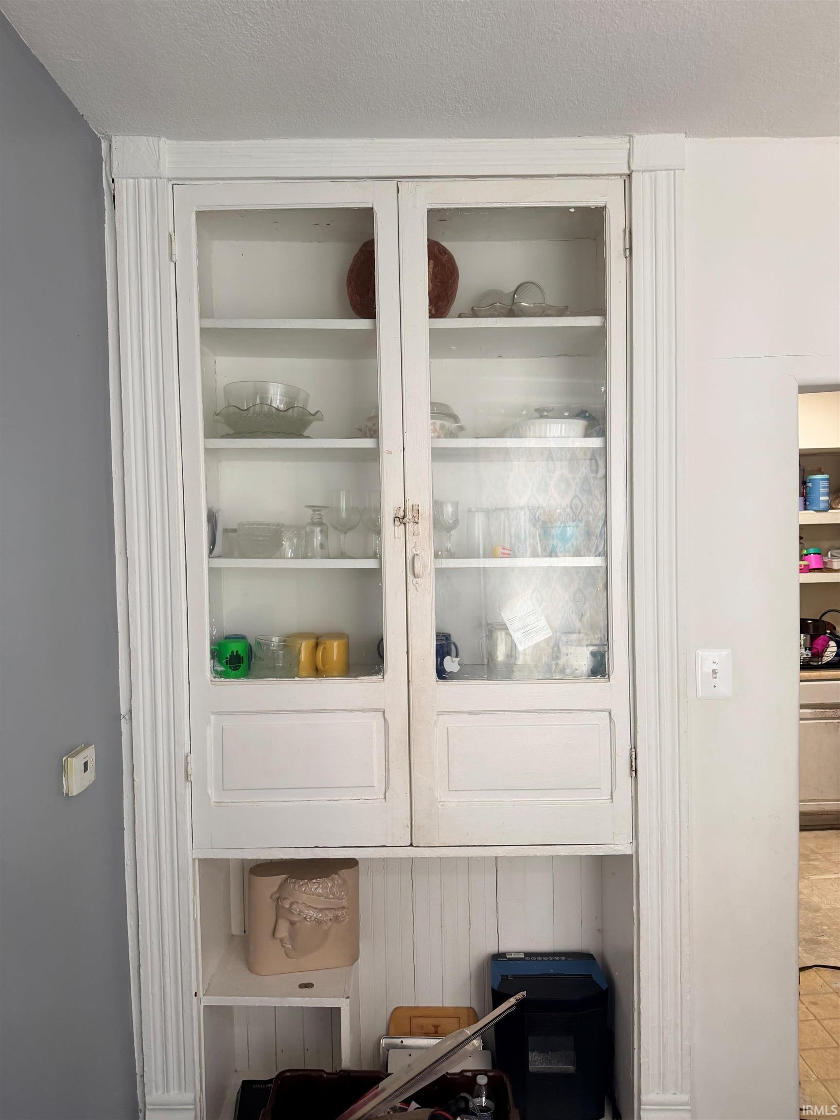 Built-in white cabinetry with glass-paneled upper doors and lower paneled doors, featuring detailed fluted trim and crown molding