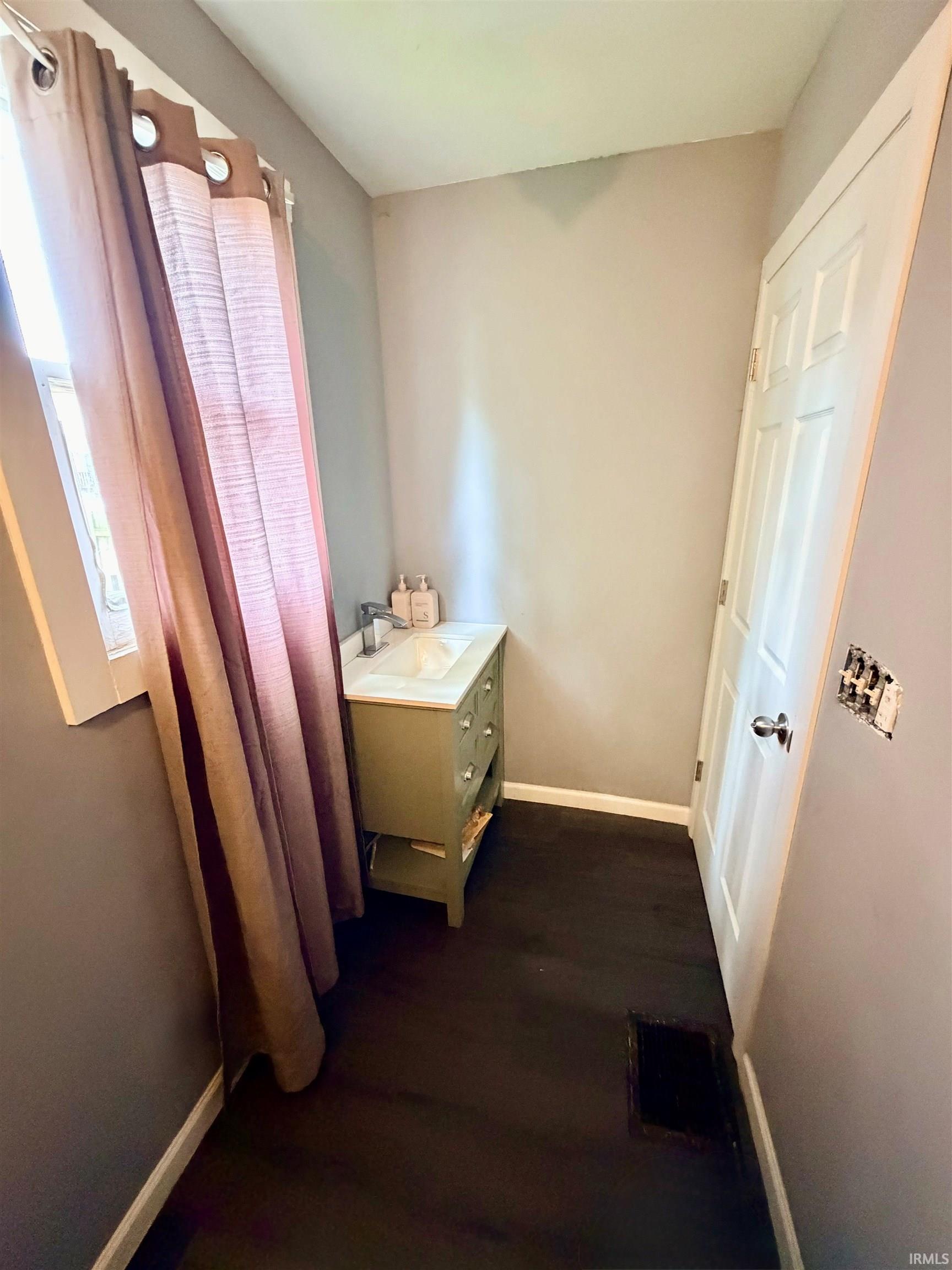 Bathroom featuring a vanity with an integrated sink, dark wood-finish flooring, and a white interior door