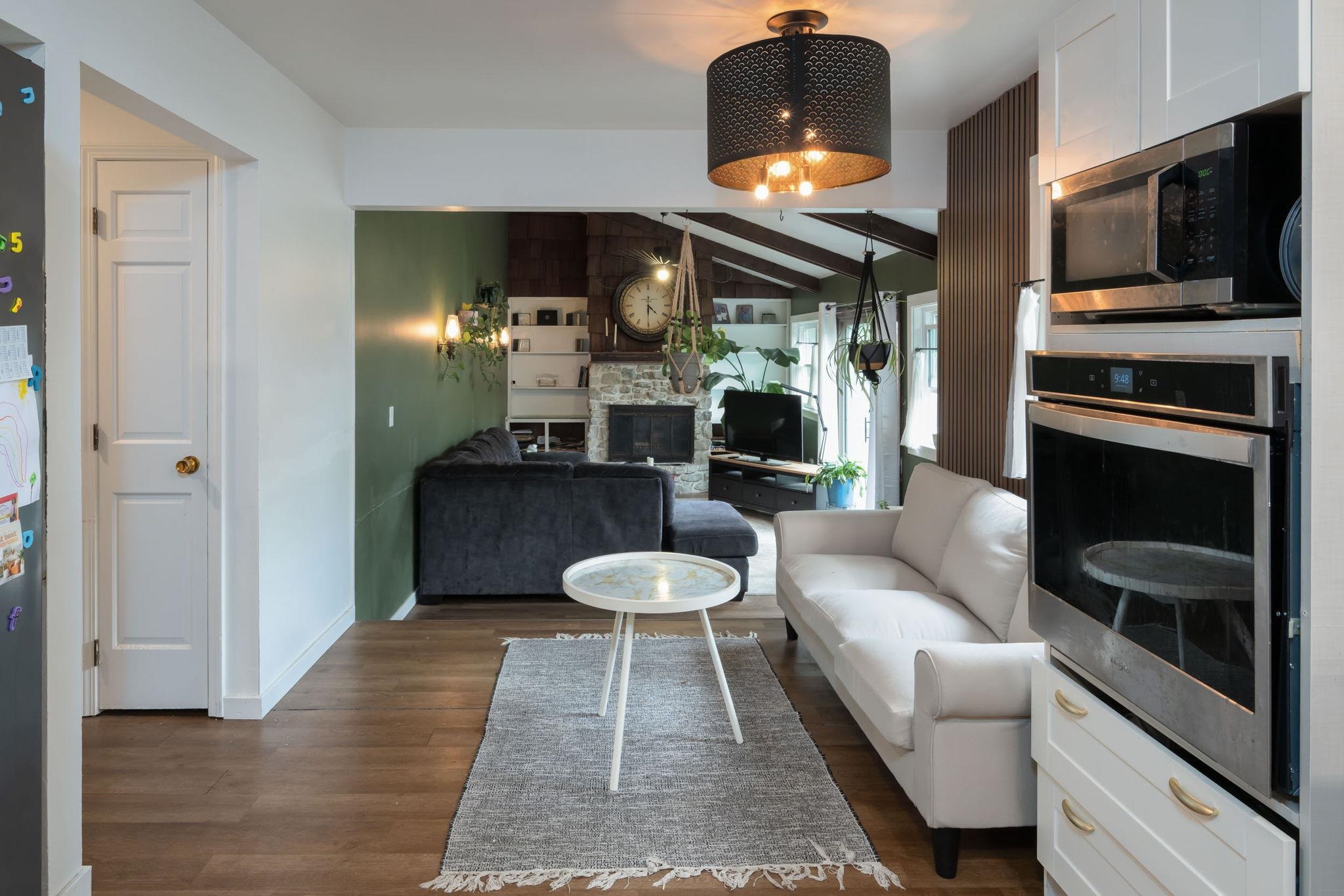 Open-concept living area with wood-finish flooring, a built-in wall oven and microwave, and a decorative ceiling light fixture