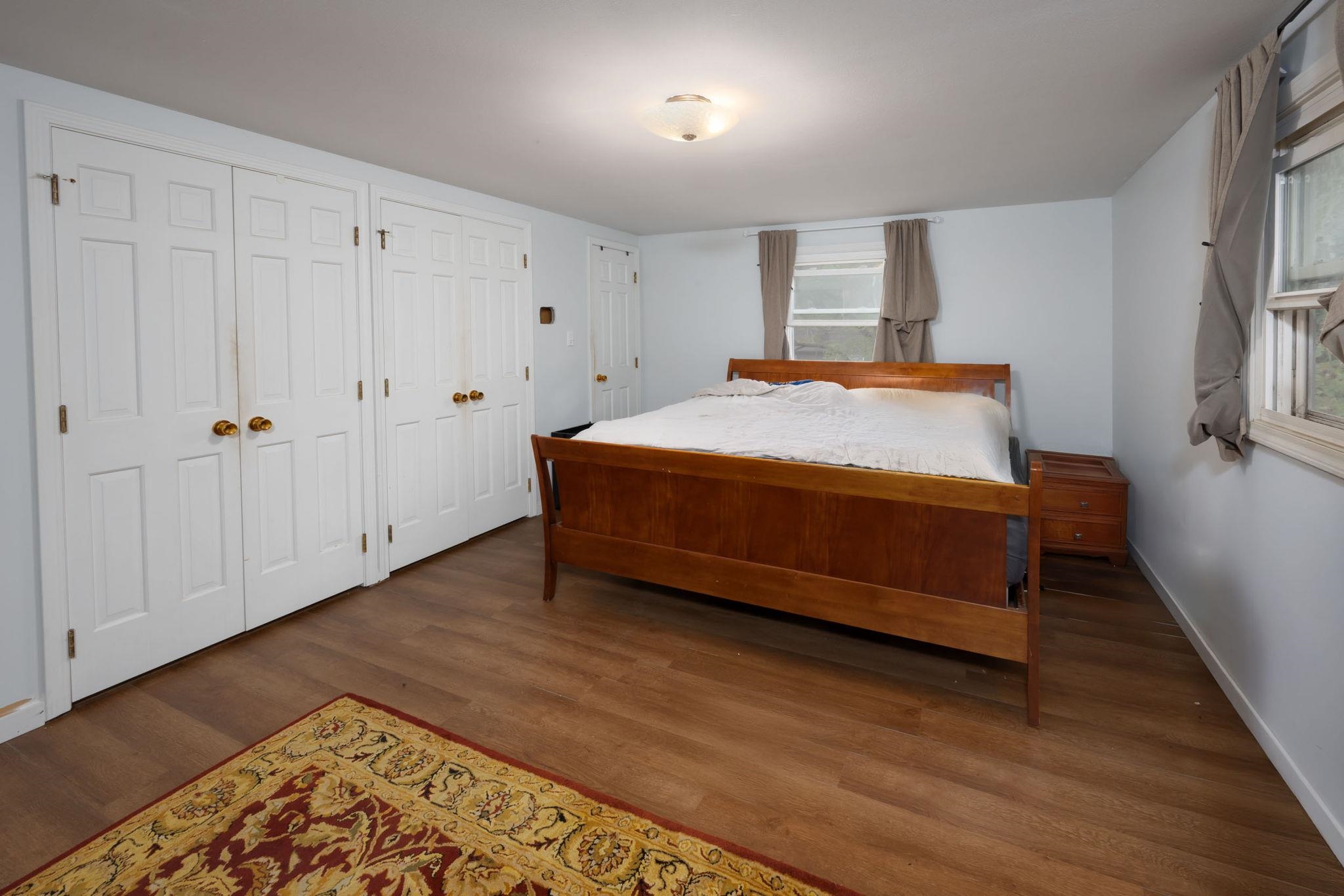 Bedroom featuring wood-finish flooring, light blue walls, and a ceiling-mounted light fixture