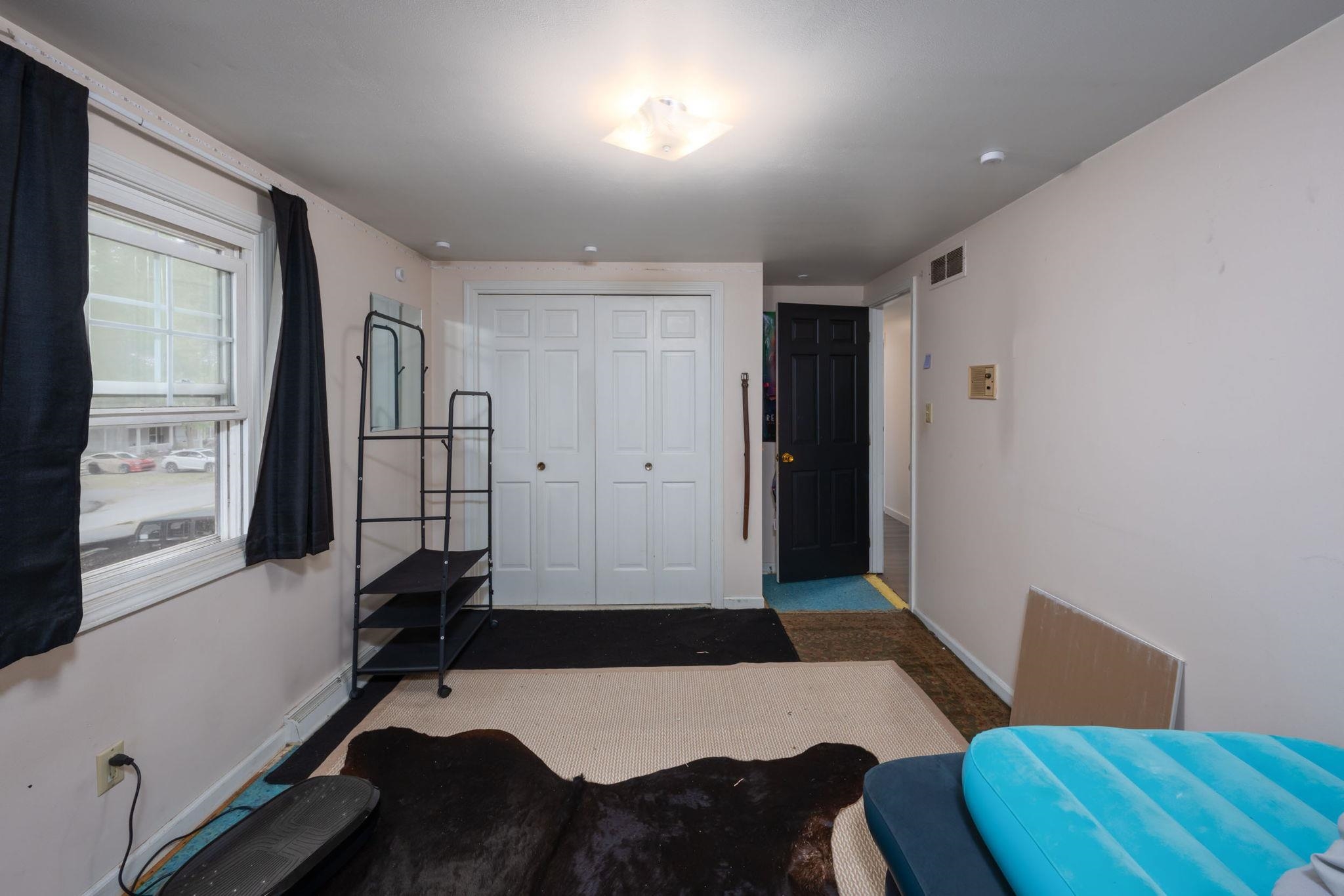 White bi-fold closet doors with black hardware, a black paneled interior door, and a single window with white trim