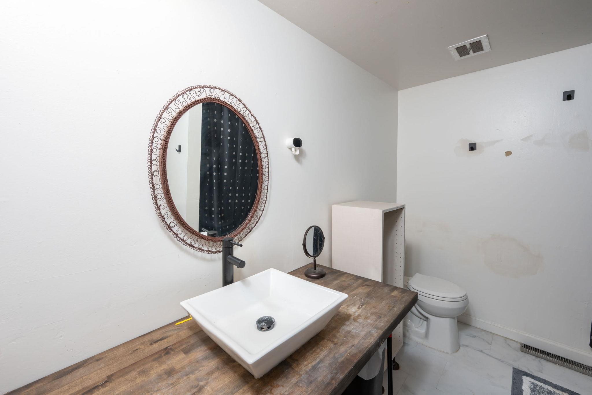Bathroom featuring a vessel sink, wood-finish countertop, and decorative framed mirror