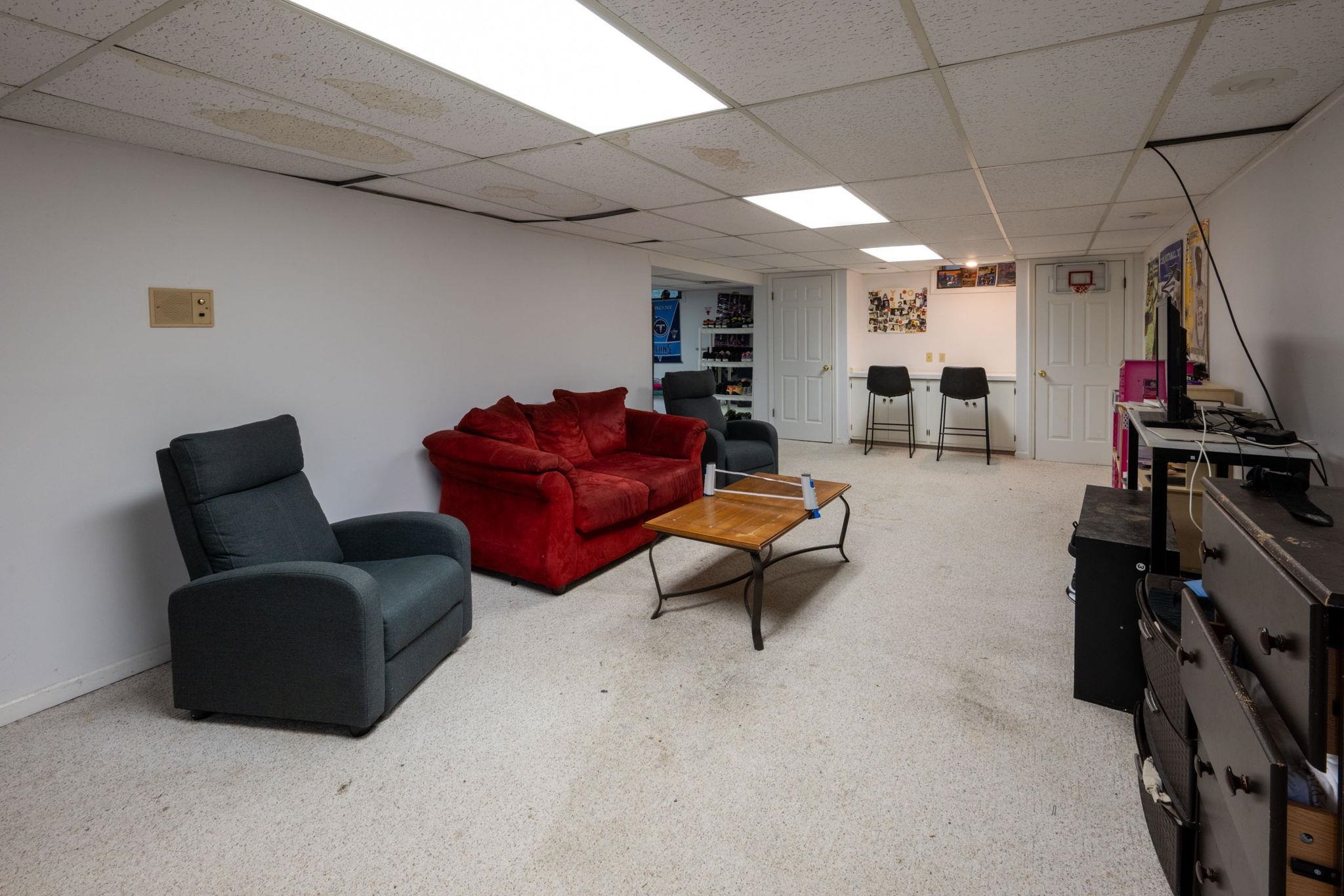 Spacious lower-level room featuring white walls and a light-colored carpet