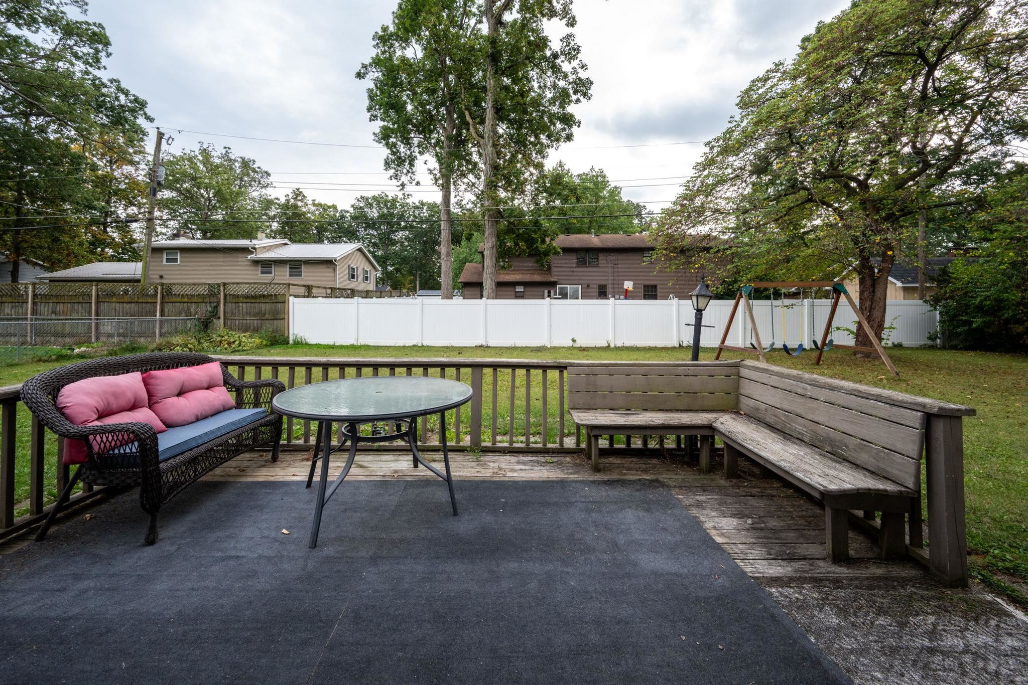 Expansive wood-plank deck featuring built-in corner seating and a black outdoor rug