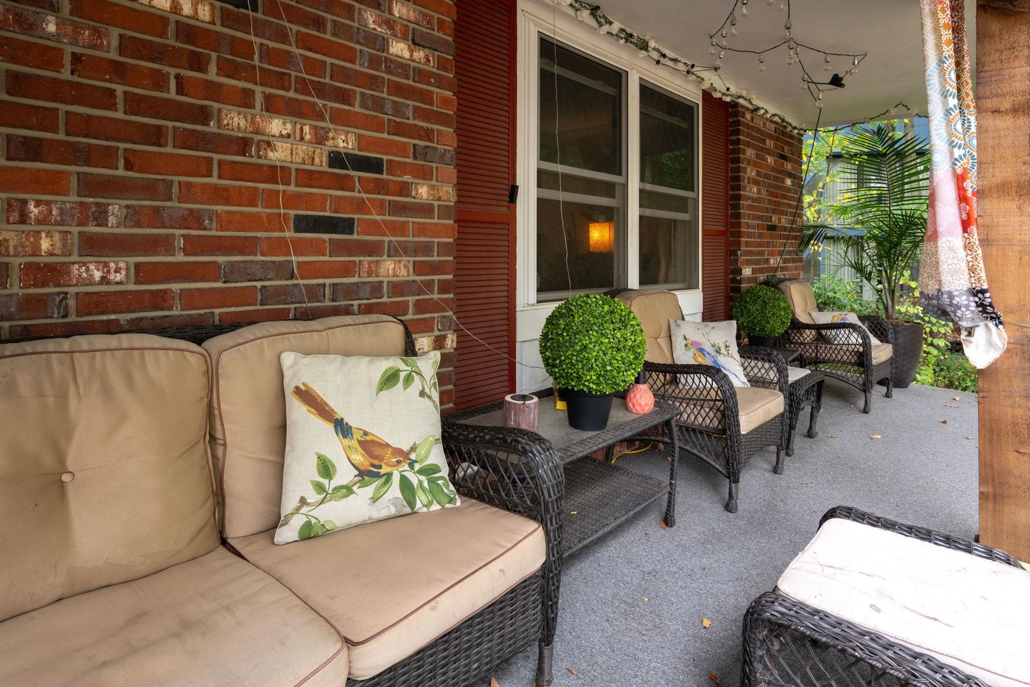 Covered porch with exposed brick facade and red window shutters
