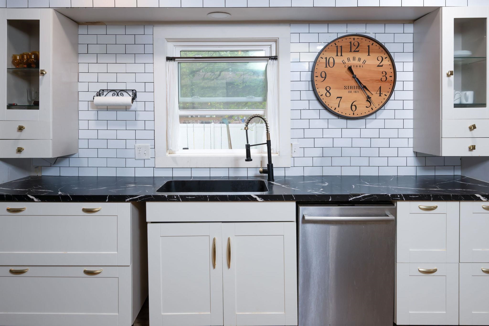 Kitchen featuring white cabinetry, black stone-finish countertops, and a white subway tile backsplash