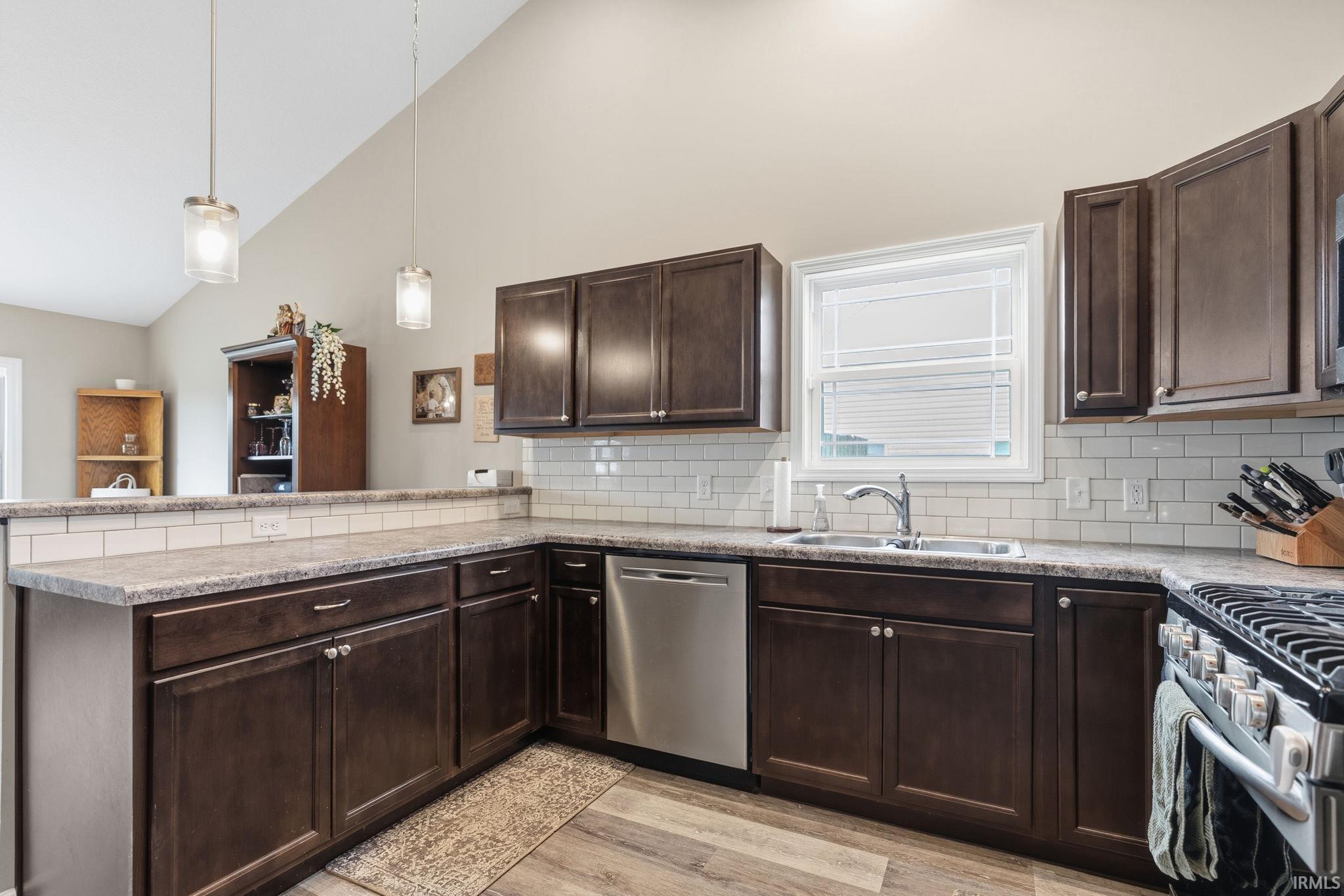 Kitchen featuring dark wood-finish cabinetry, light-toned countertops, and a white subway tile backsplash
