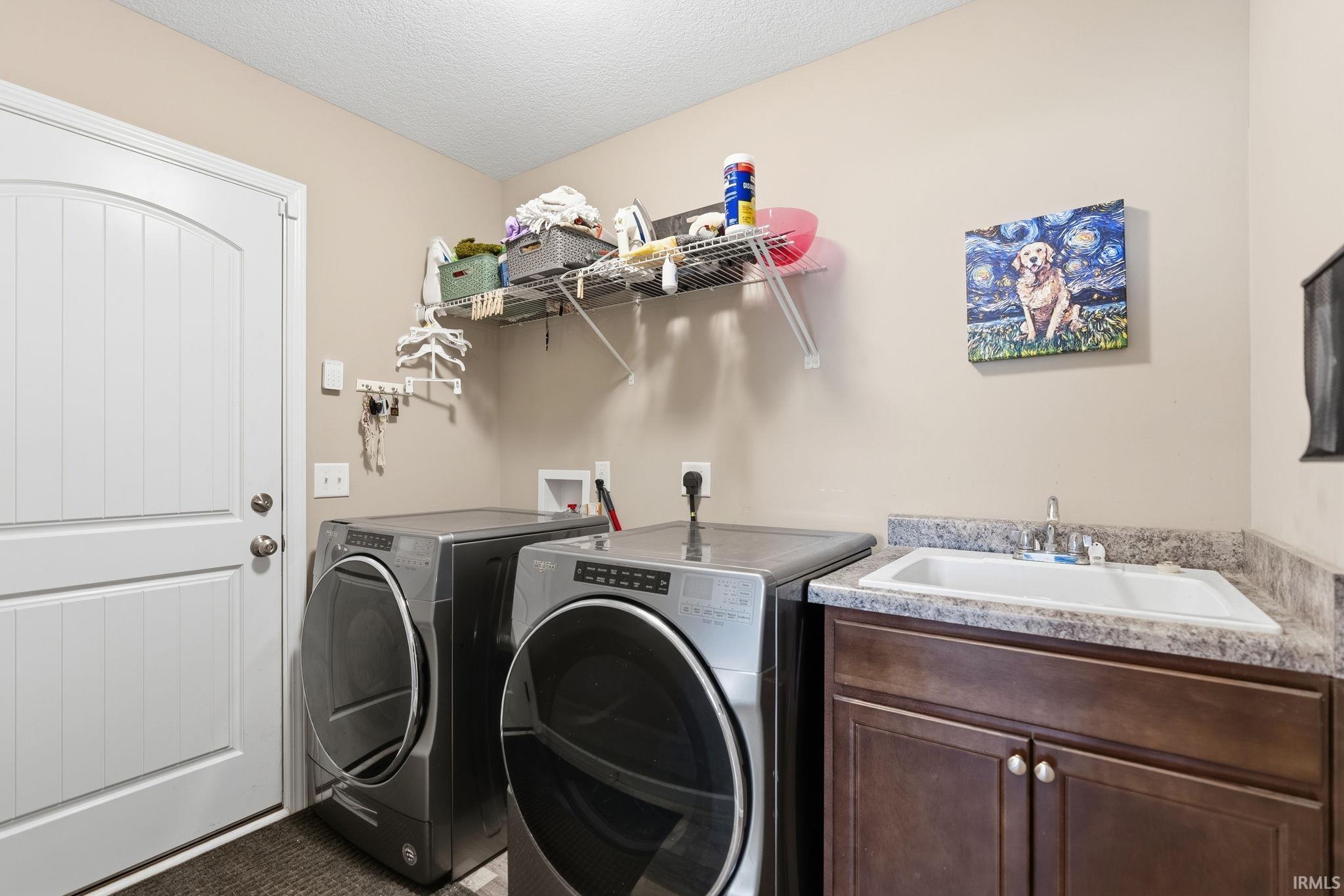 Dedicated laundry area featuring a utility sink, dark wood-finish cabinetry, and a textured countertop