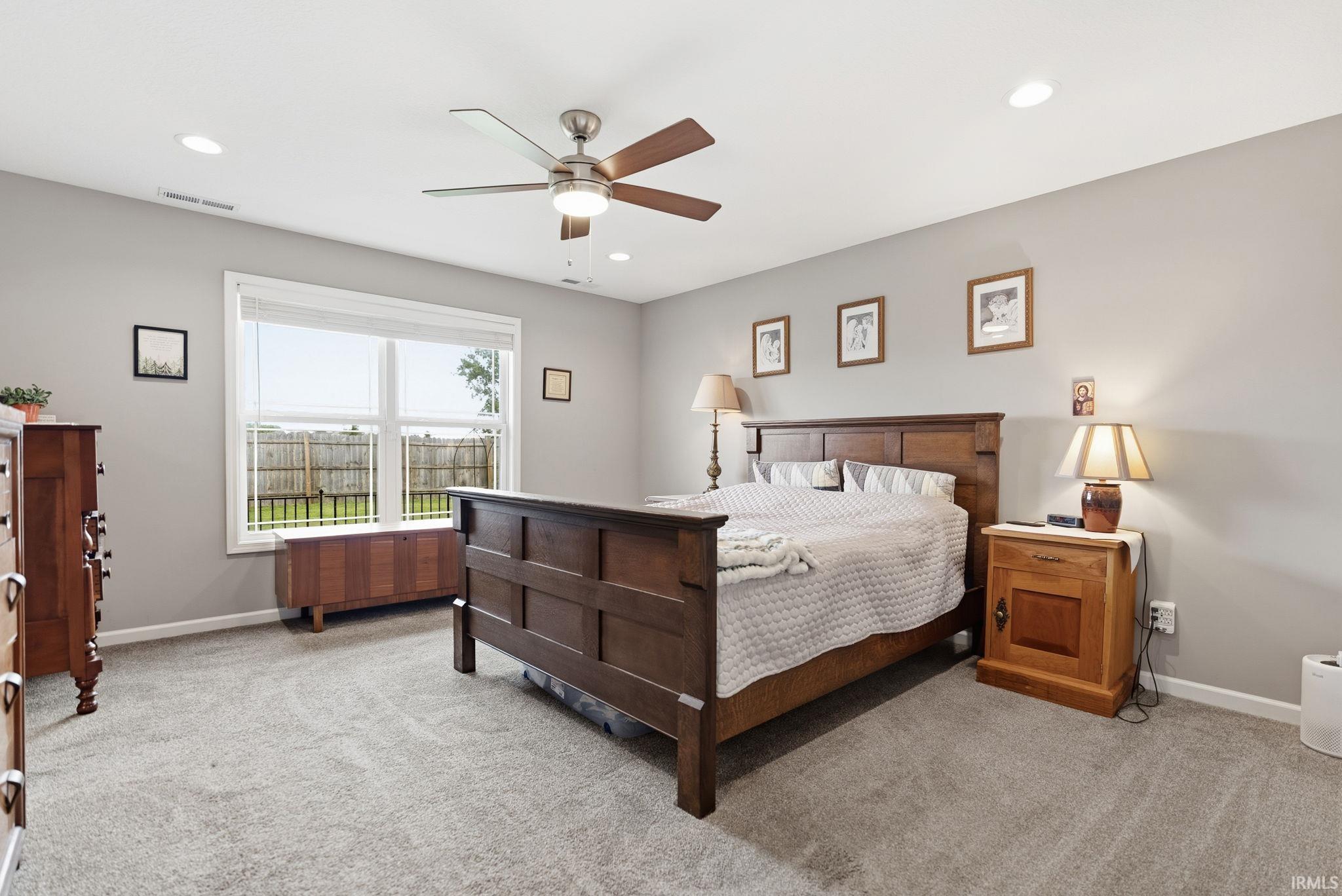 Spacious room featuring neutral wall tones, gray carpeting, a ceiling fan with integrated lighting, recessed lighting, and a large window providing outdoor visibility