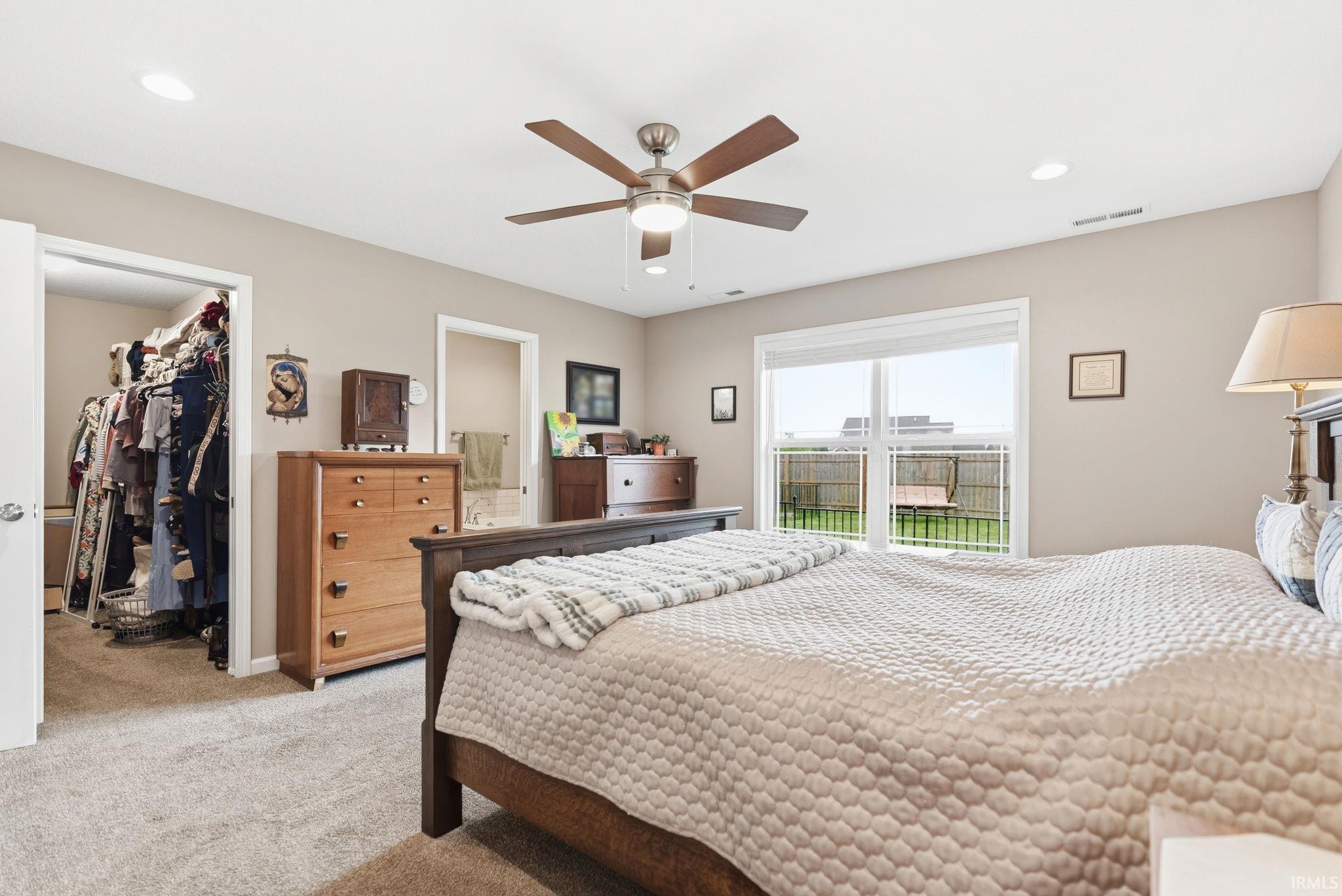 Carpeted bedroom featuring a ceiling fan with integrated lighting, recessed lighting, and a large sliding glass door