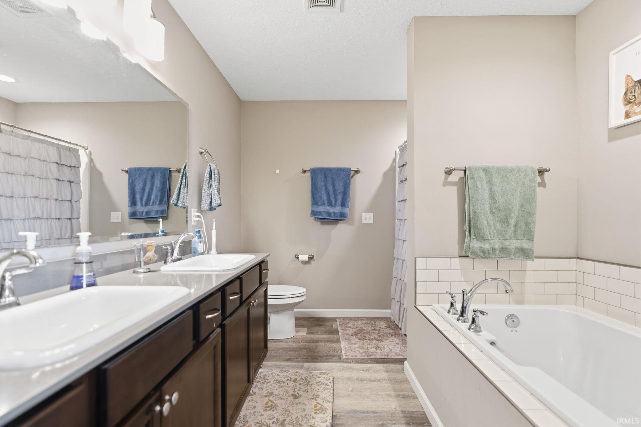 Bathroom featuring a double vanity with ample counter space, rich wood-finish cabinetry, and individual rectangular sinks