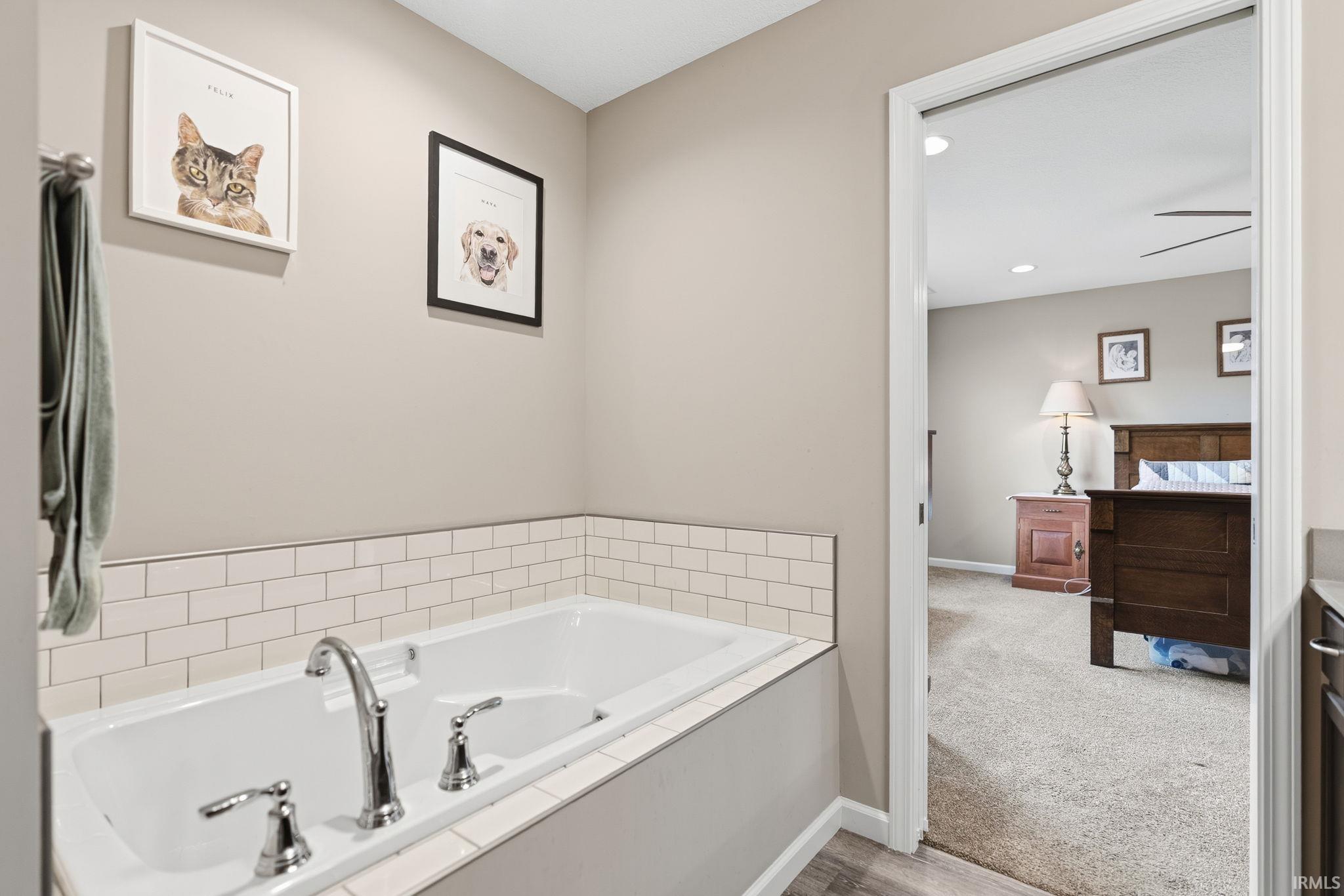 Built-in bathtub featuring subway tile surround, chrome fixtures, and wood-finish flooring