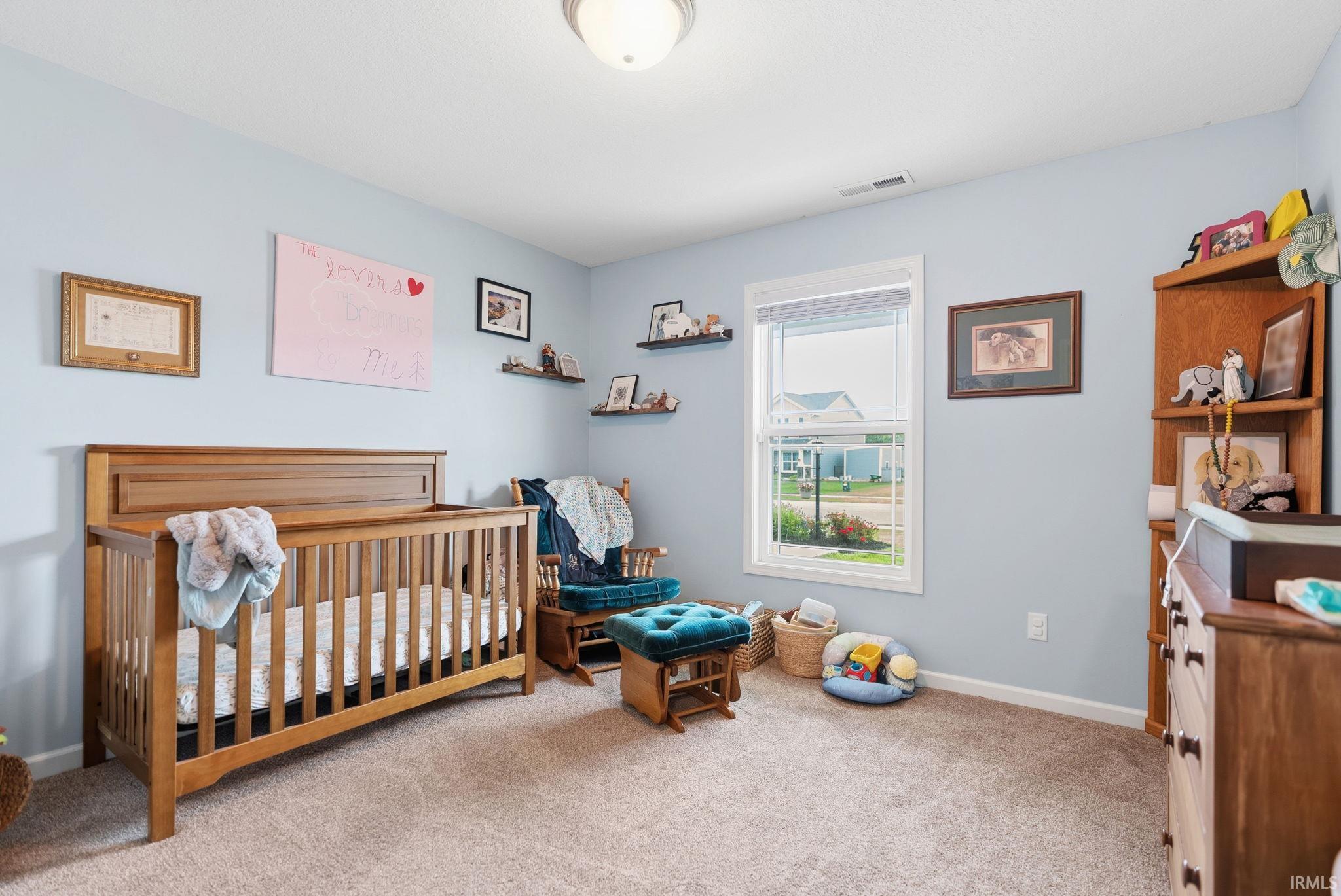 Carpeted room featuring a single window with blinds, light blue wall paint, a flush-mount ceiling light fixture, and white trim