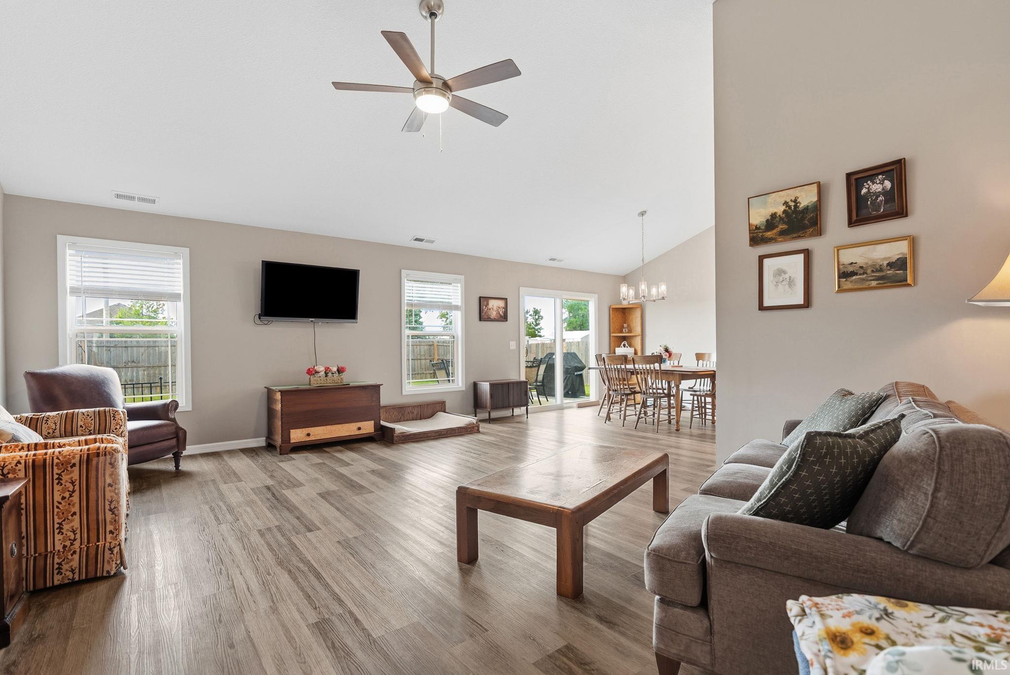 Spacious living area featuring vaulted ceilings, wood-finish flooring, and neutral wall tones