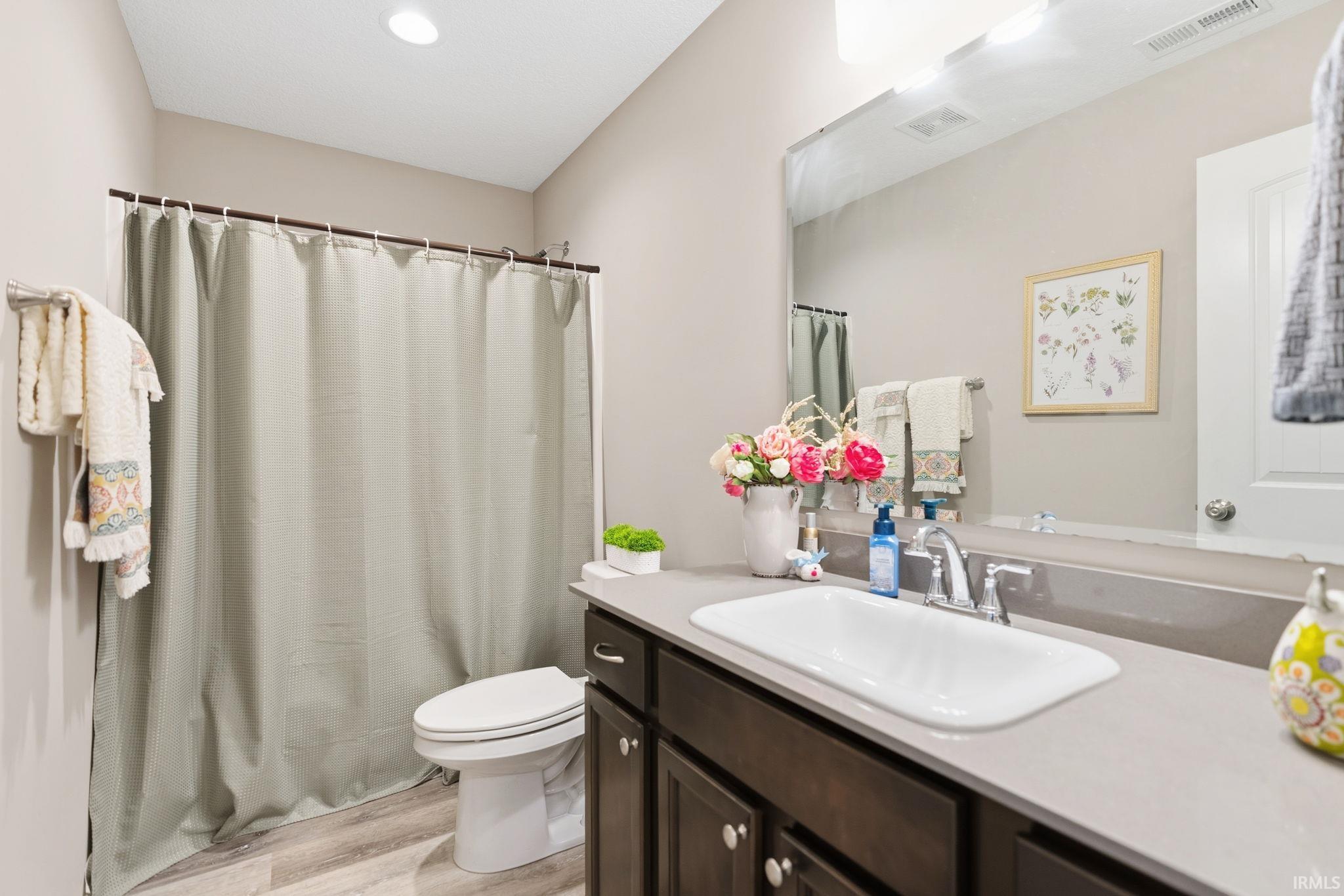 Bathroom featuring a dark wood-finish vanity with a light countertop, an undermount sink, and chrome fixtures