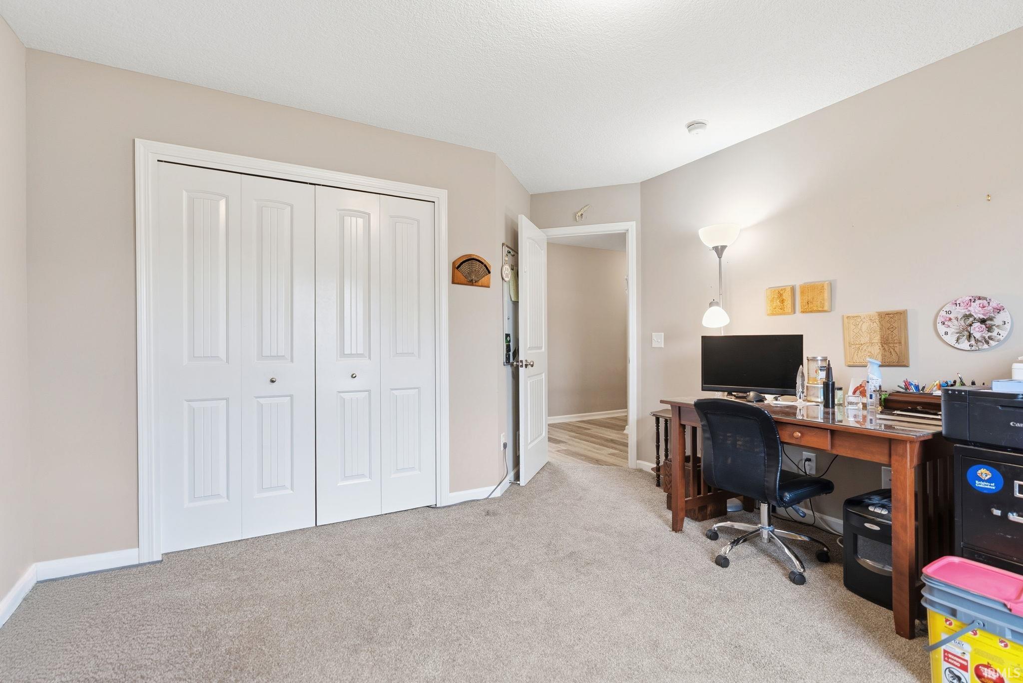 Carpeted room with bi-fold closet doors, neutral wall paint, and white trim