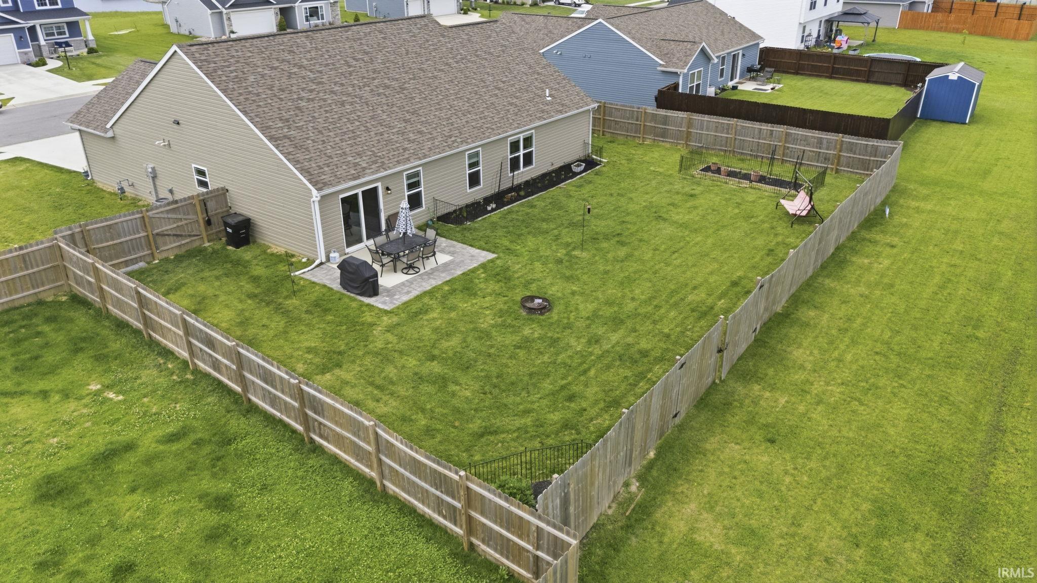 Expansive fenced backyard featuring a paver patio, sliding glass door access, and a manicured lawn