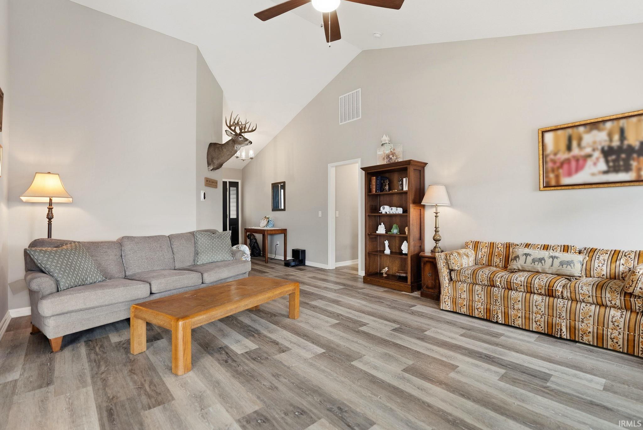 Vaulted ceiling living space featuring wood-finish flooring, a ceiling fan, and recessed lighting