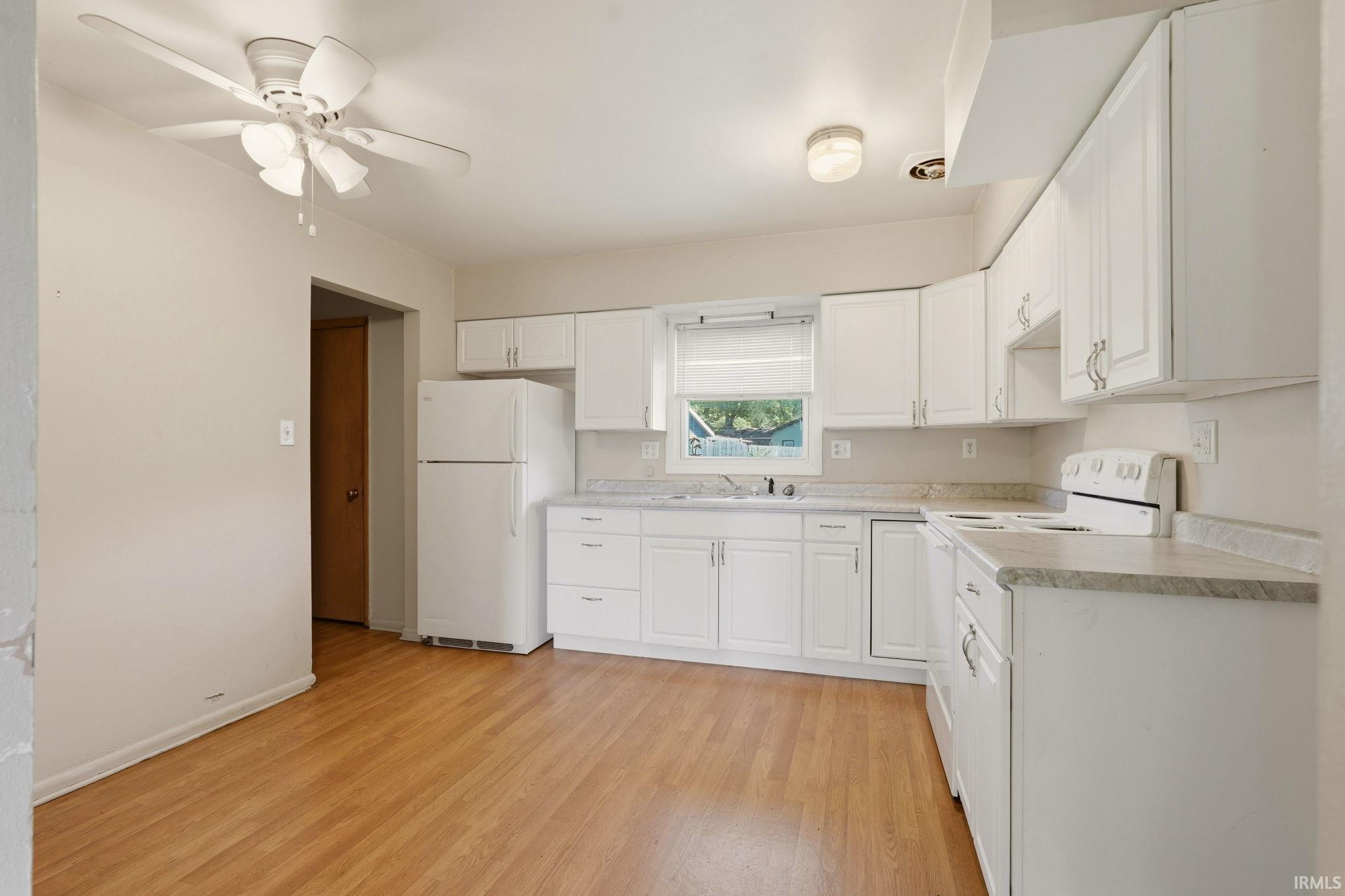 Kitchen featuring white cabinetry, light-toned countertops, and wood-finish flooring
