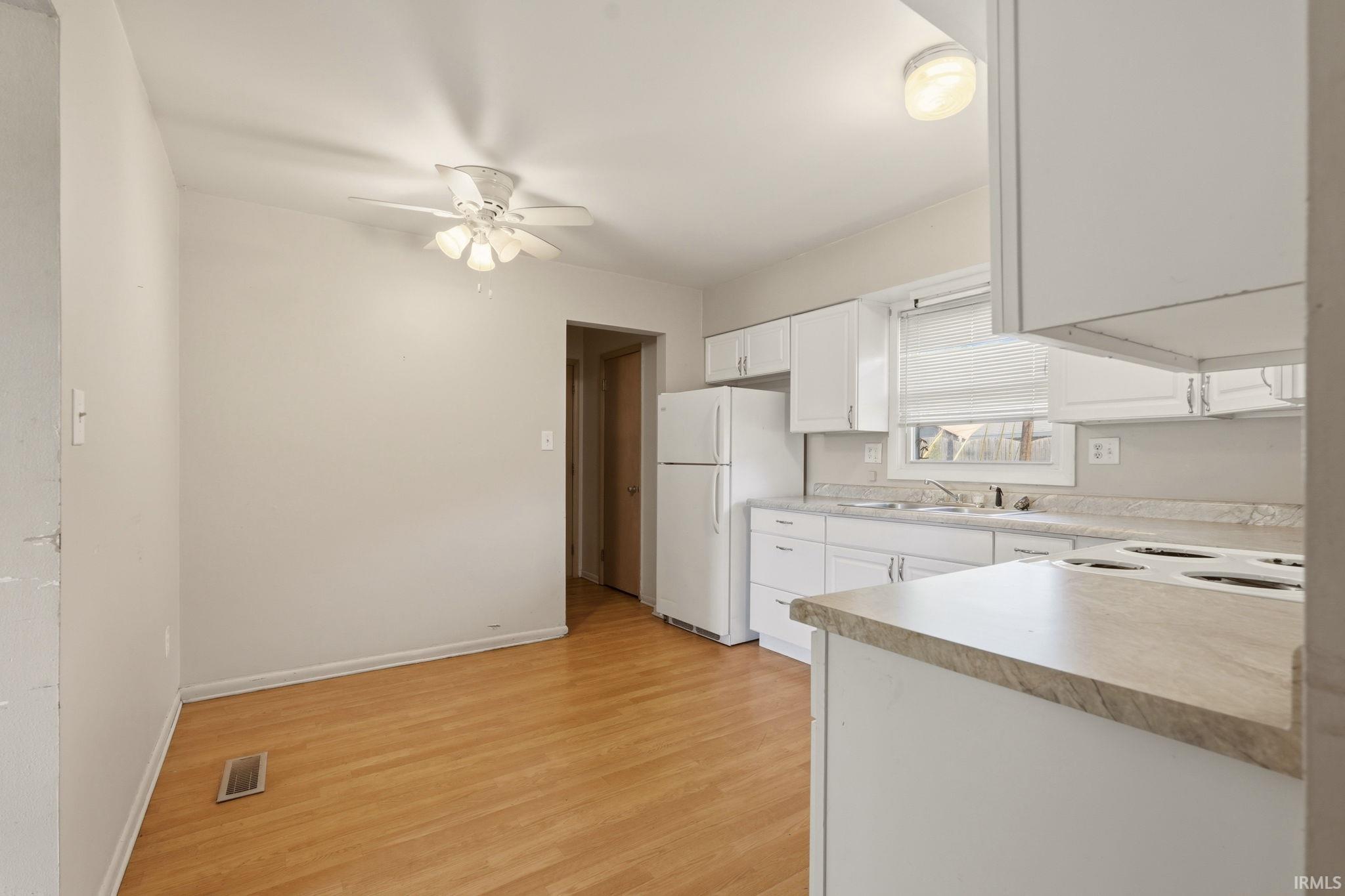 Kitchen featuring wood-finish flooring, white cabinetry, a built-in electric range, and a ceiling fan with integrated lighting