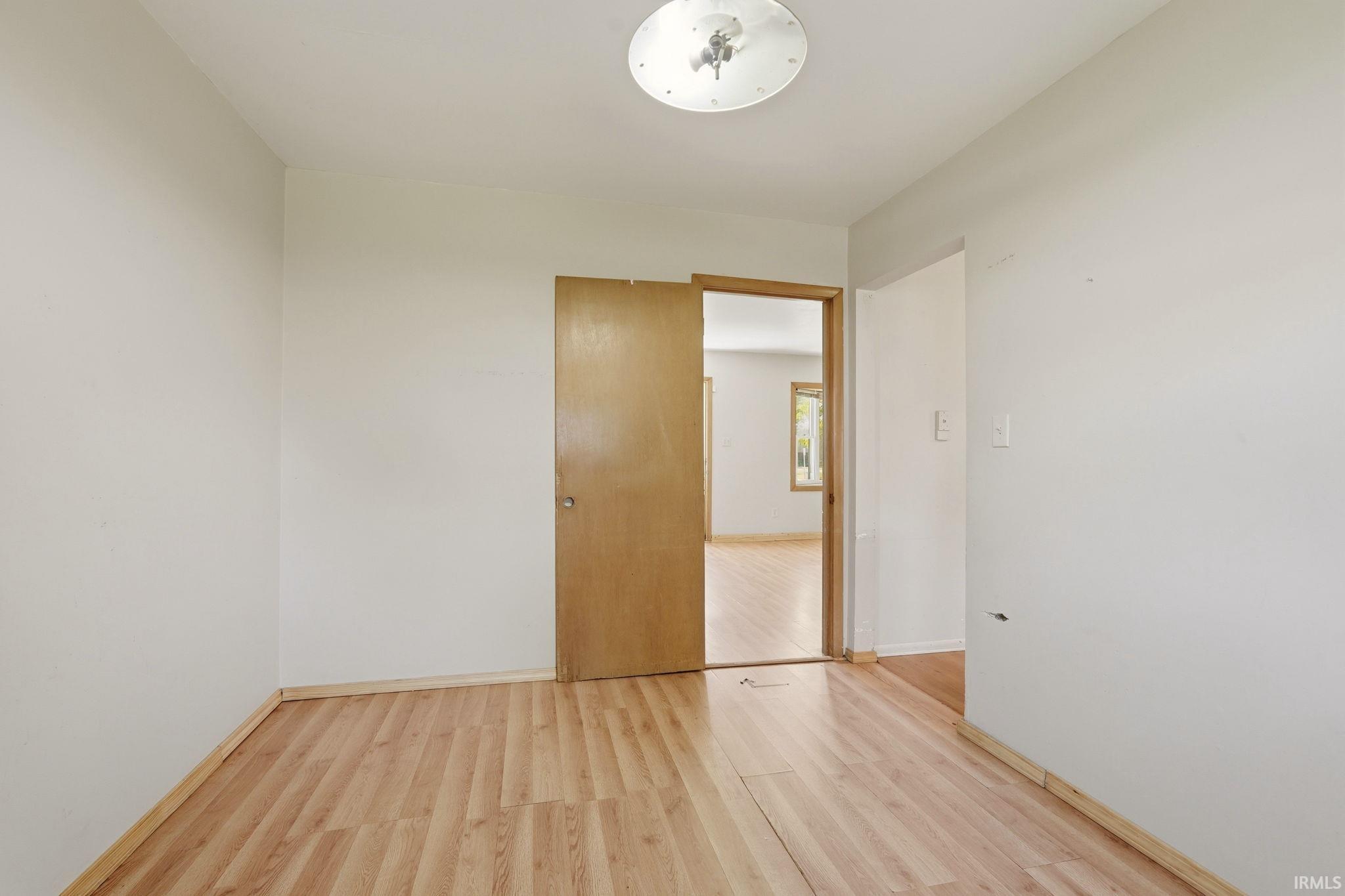 Room featuring wood-finish flooring, light-toned walls, and a ceiling-mounted light fixture