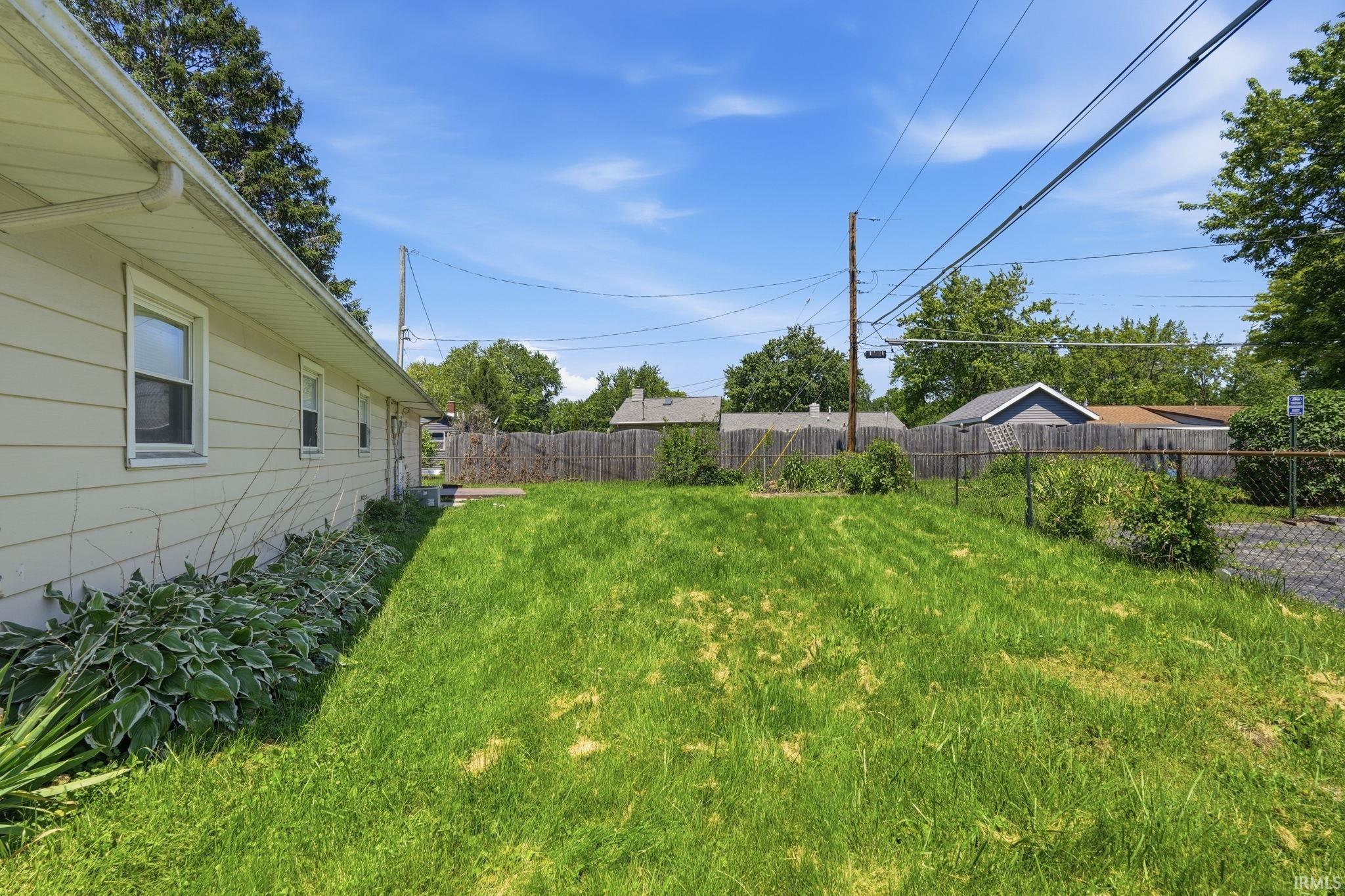 Expansive grassy yard with chain-link and wood fencing