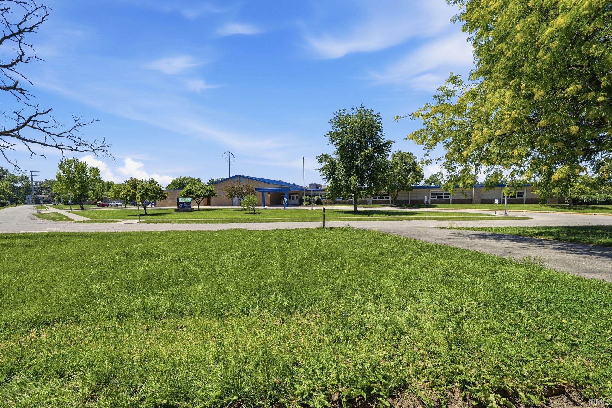 Expansive green space featuring a paved walkway and mature trees
