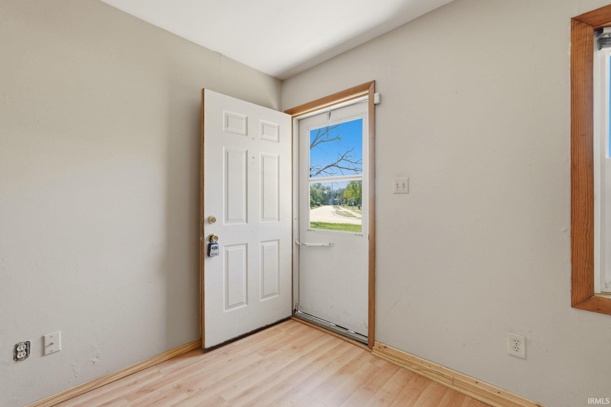 Entryway featuring a paneled door, wood-finish flooring, and light-toned wall paint