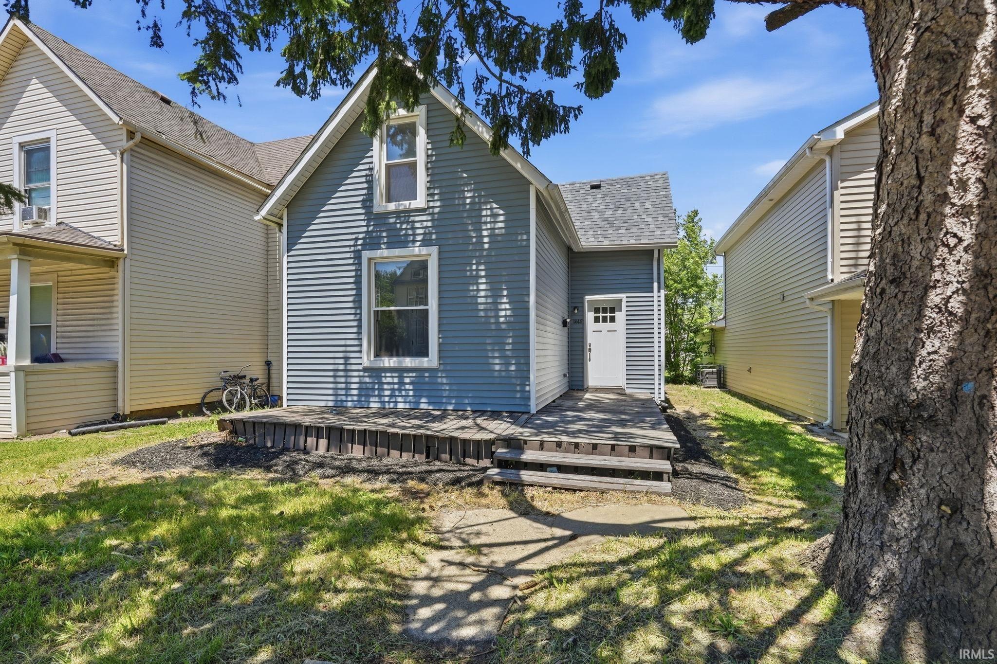 Rear exterior featuring blue horizontal siding, white trim windows, and a multi-tiered wooden deck